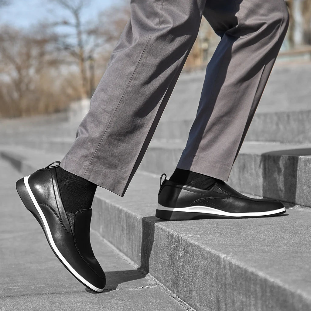 Person wearing black shoes and gray pants climbing stairs outdoors.