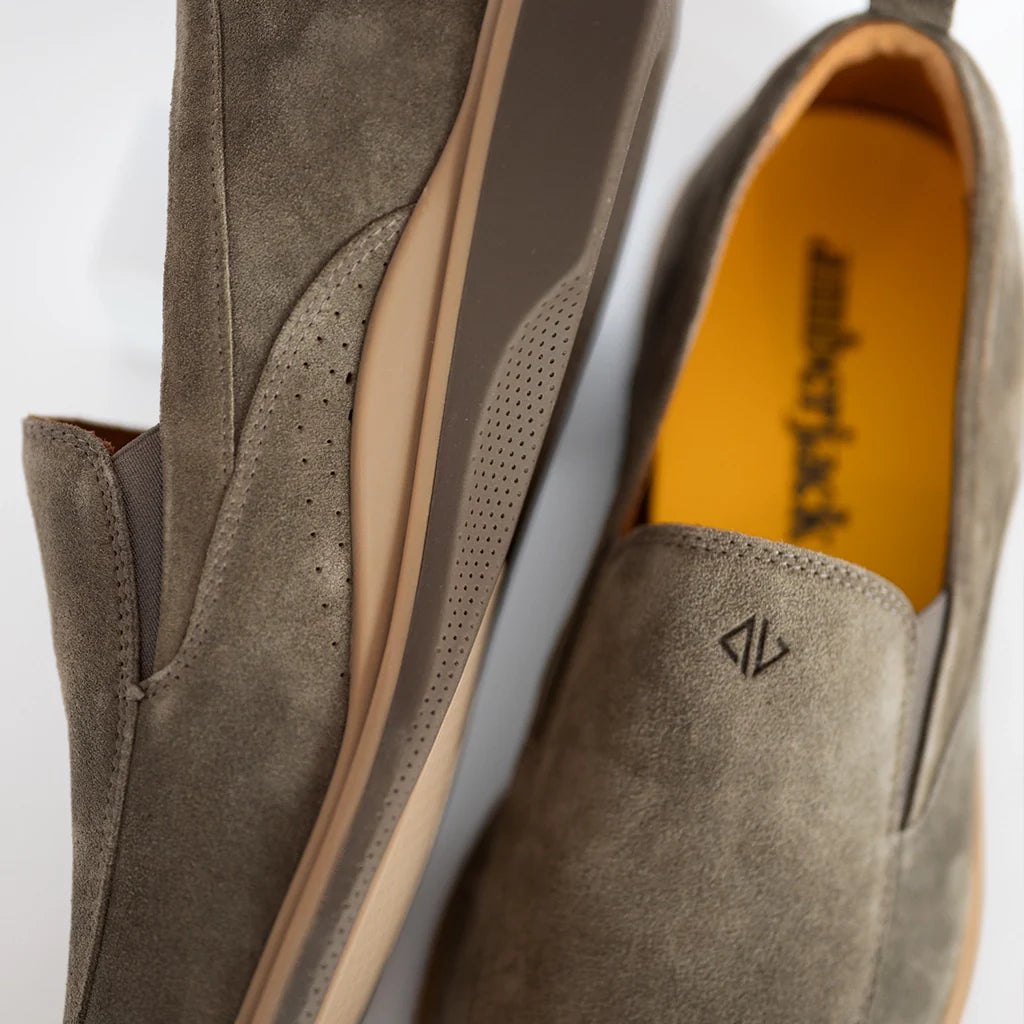 Close-up of gray suede shoes with a brand logo on a white background