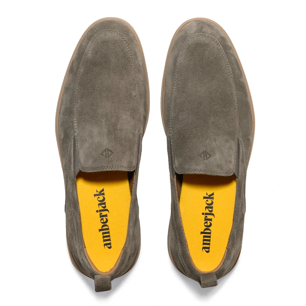 Pair of gray suede shoes with yellow insoles on a white background