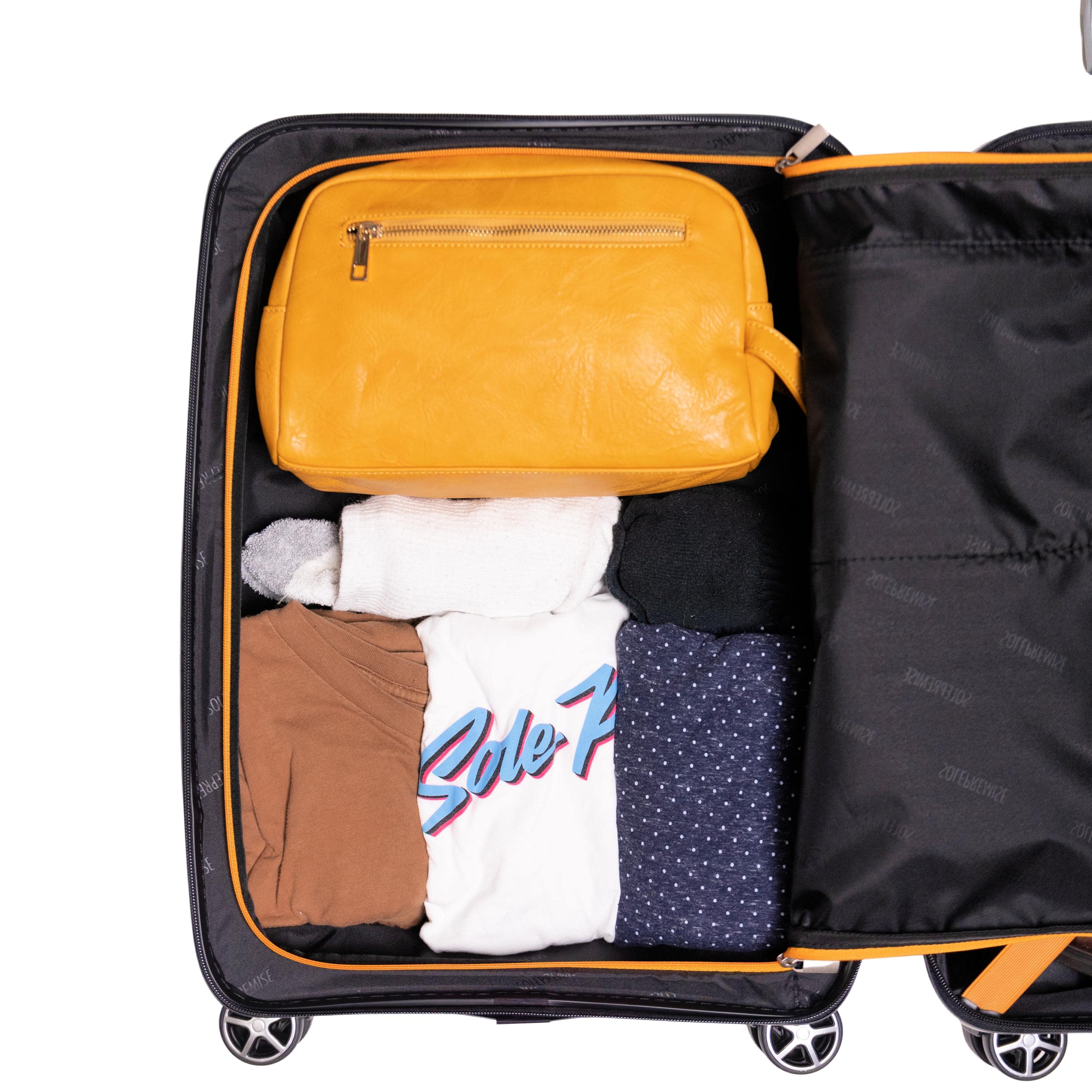Open suitcase with clothes and a yellow toiletry bag on a white background