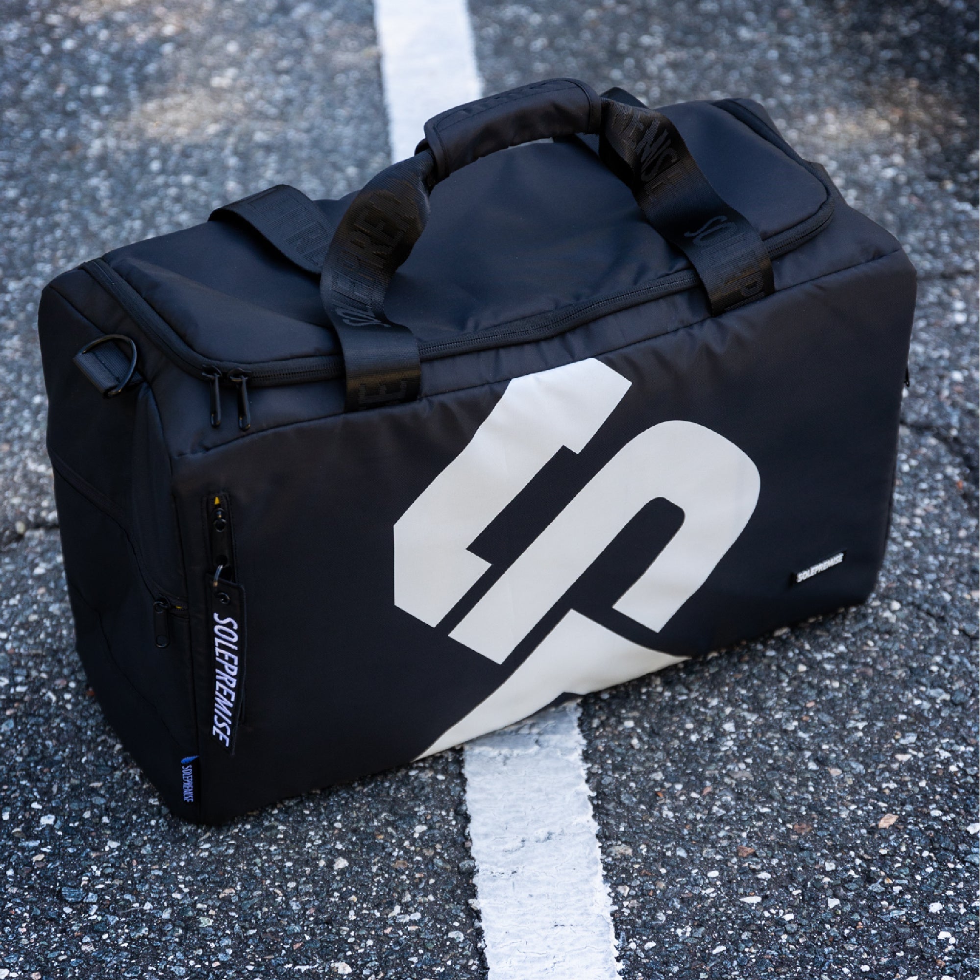 Black duffel bag with a logo on a road