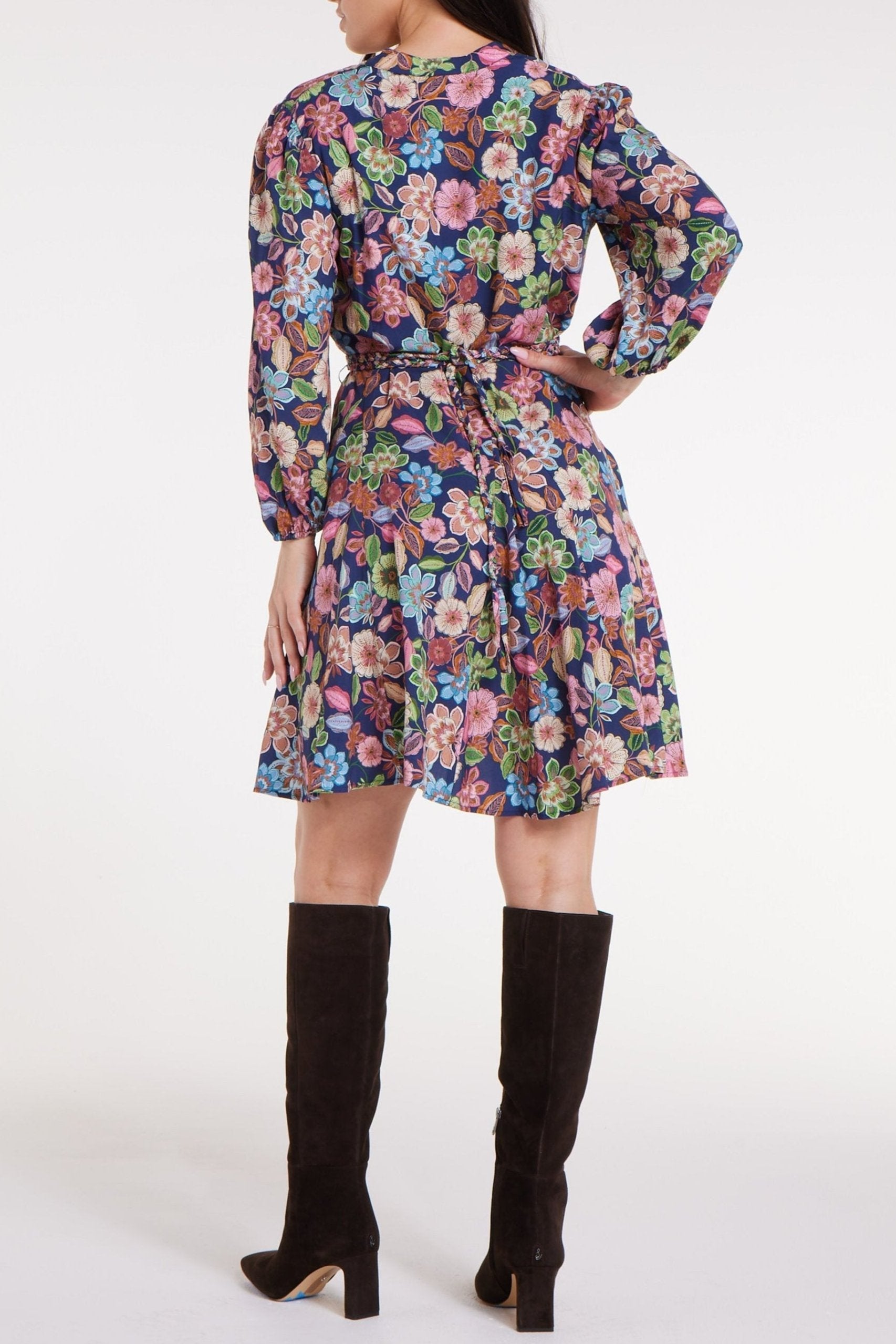 Woman wearing a colorful floral dress with long sleeves on a white background