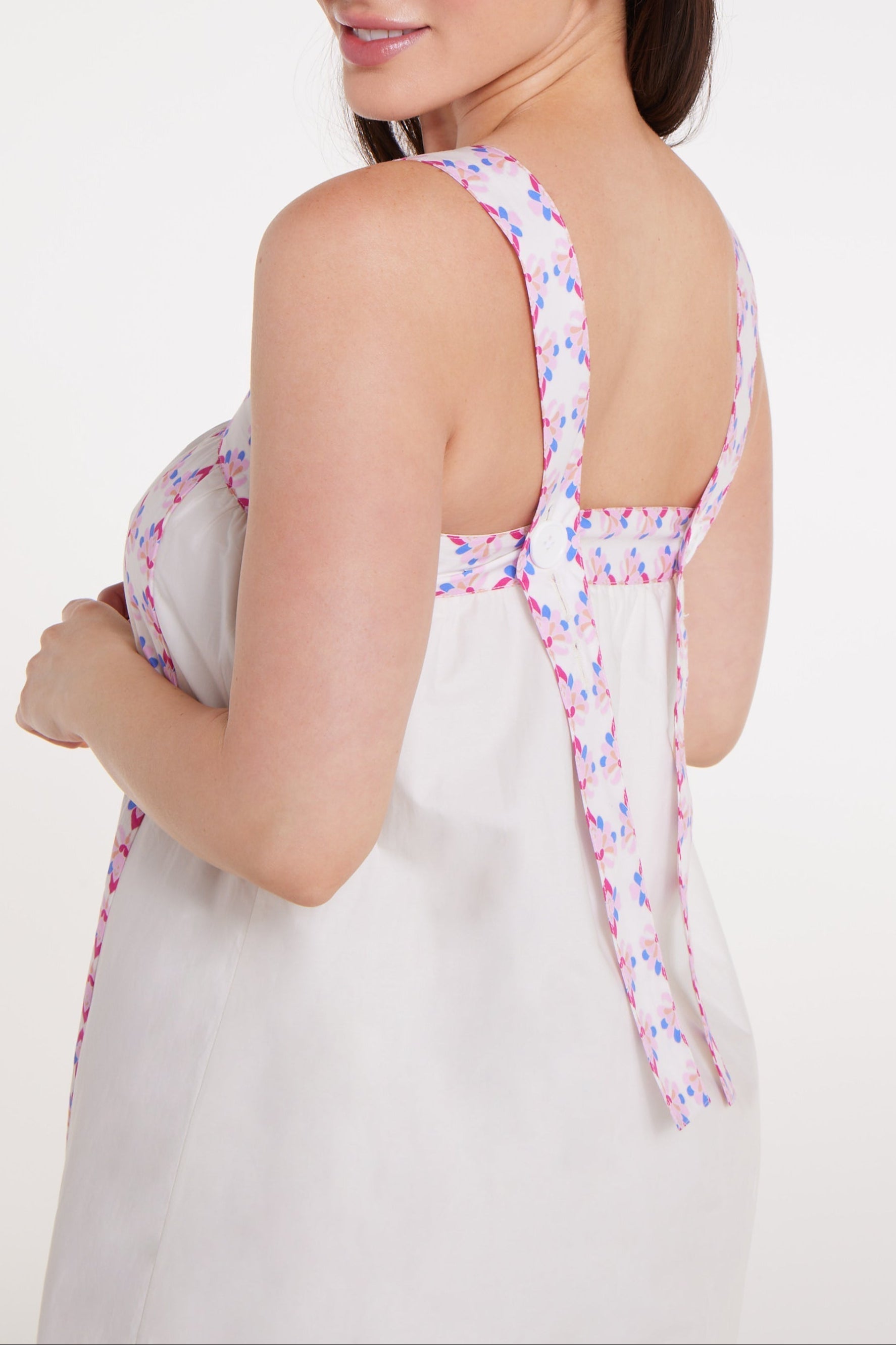 Woman wearing a white dress with colorful floral straps on a white background