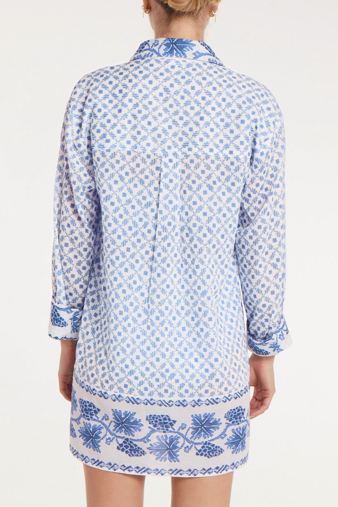 Woman wearing a blue and white patterned dress with a plain background