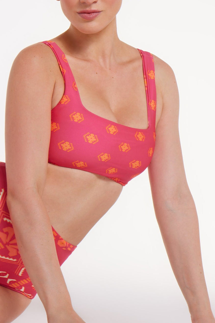 Woman wearing a pink bikini with orange patterns on a white background