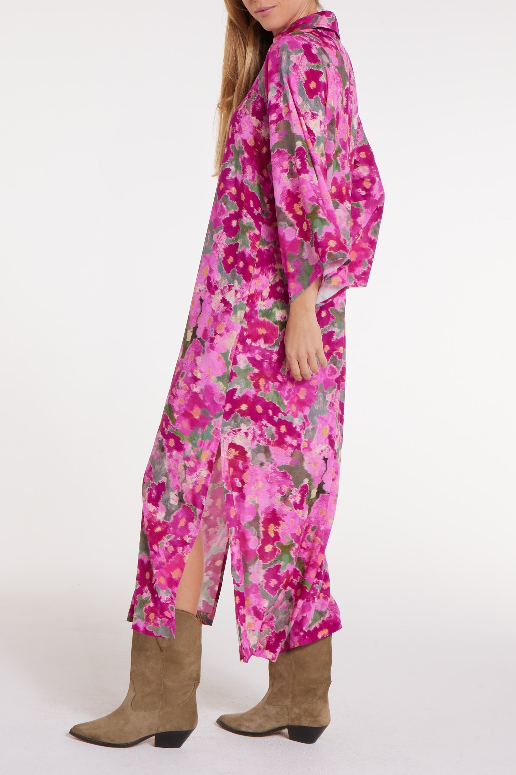 Woman wearing a pink floral dress with brown boots on a white background