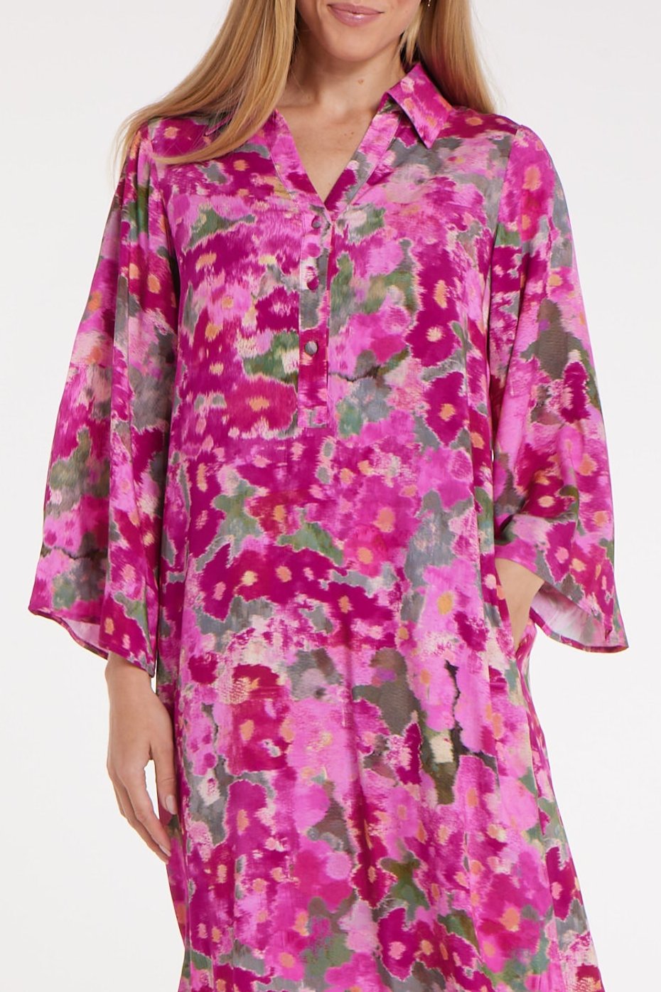 Woman wearing a vibrant pink floral dress on a white background