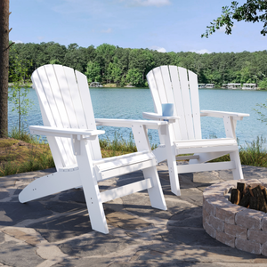 Two white Adirondack chairs by a lake with trees in the background