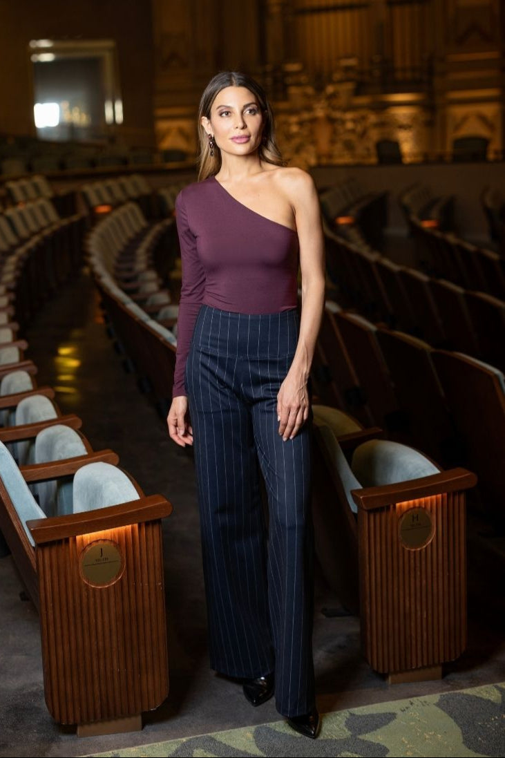 Woman in a purple top and blue striped pants standing in an auditorium.