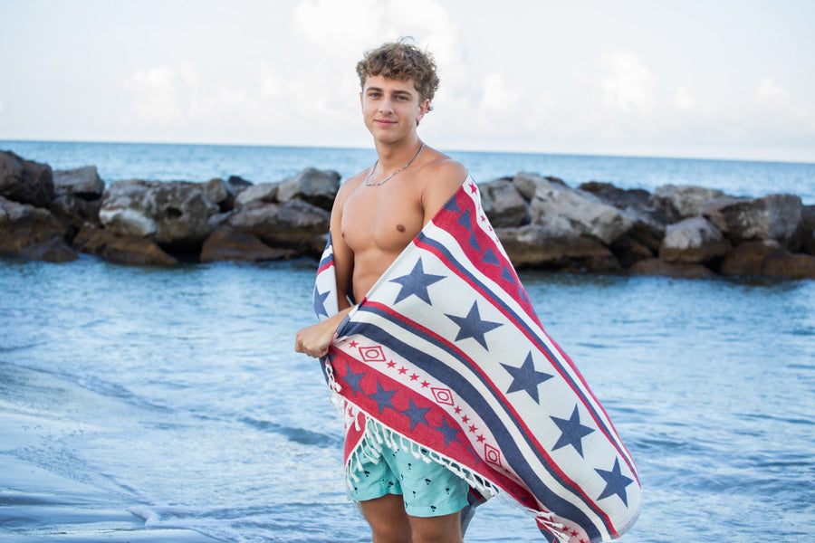 Man holding a towel with star pattern by the ocean
