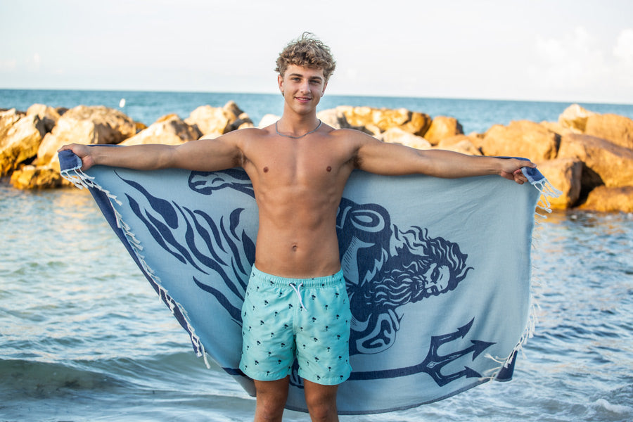 Man holding a towel with a logo on a beach