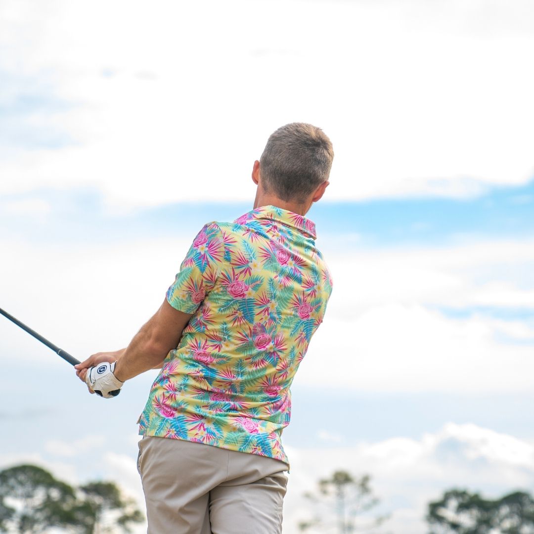 Man in a colorful shirt holding a golf club with a clear sky background