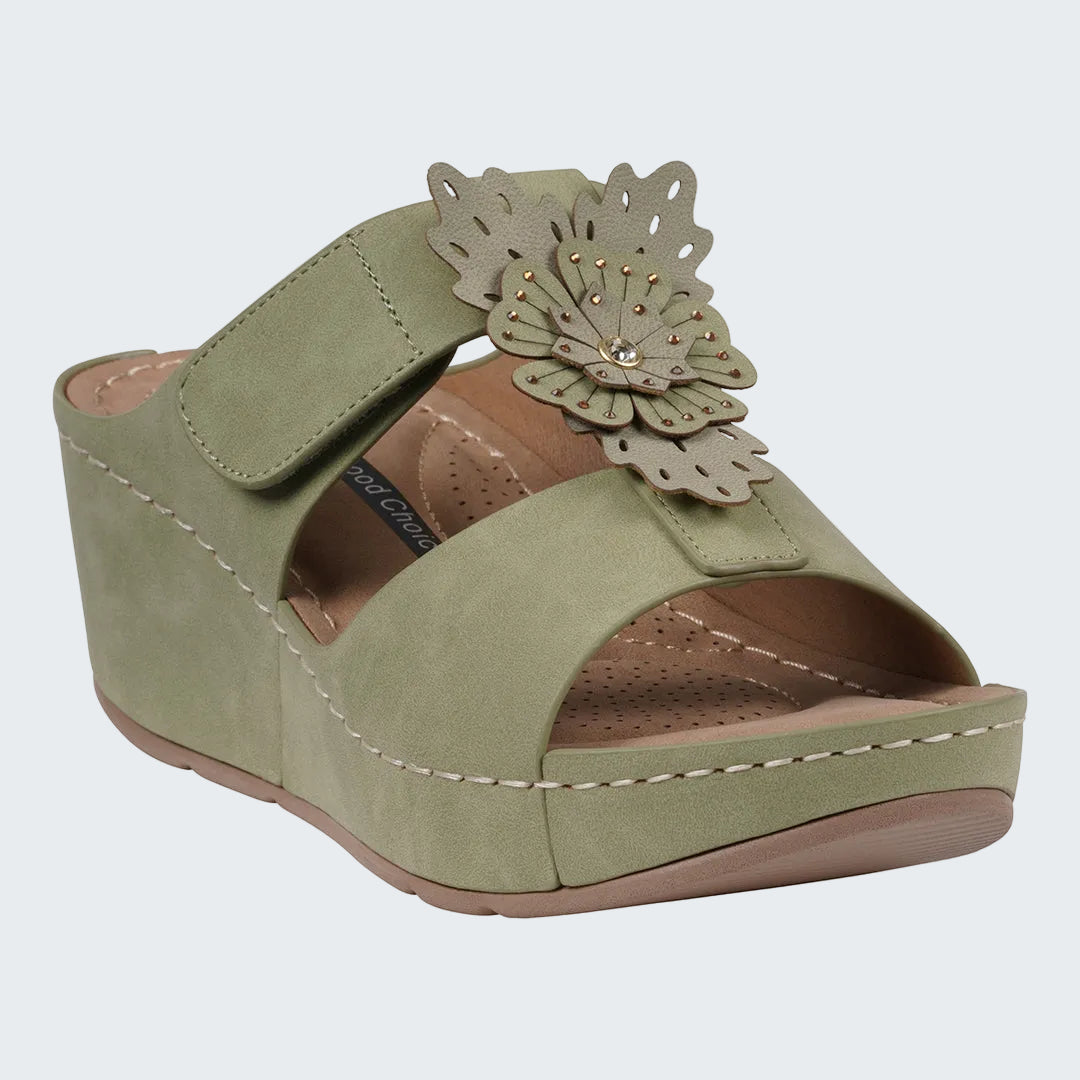 Green wedge sandal with a decorative flower on a white background