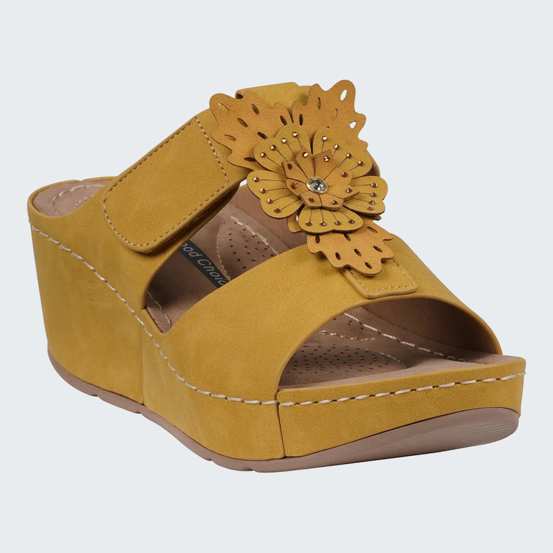 Yellow wedge sandal with a decorative flower on a white background