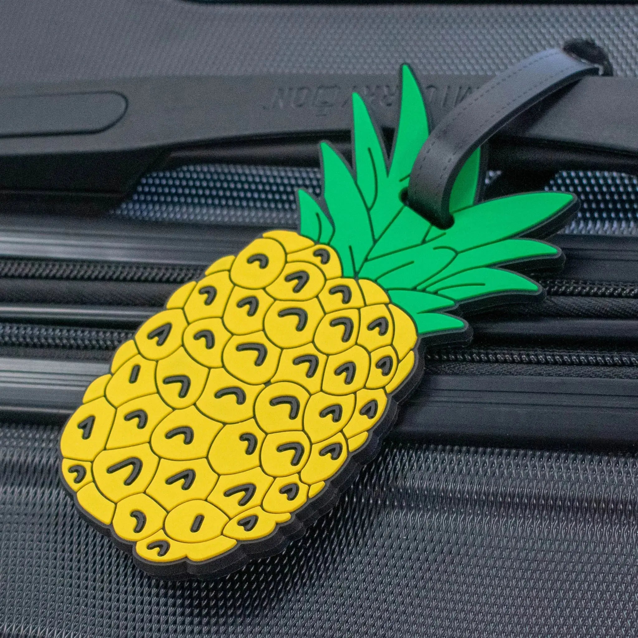 Pineapple-shaped luggage tag attached to a suitcase