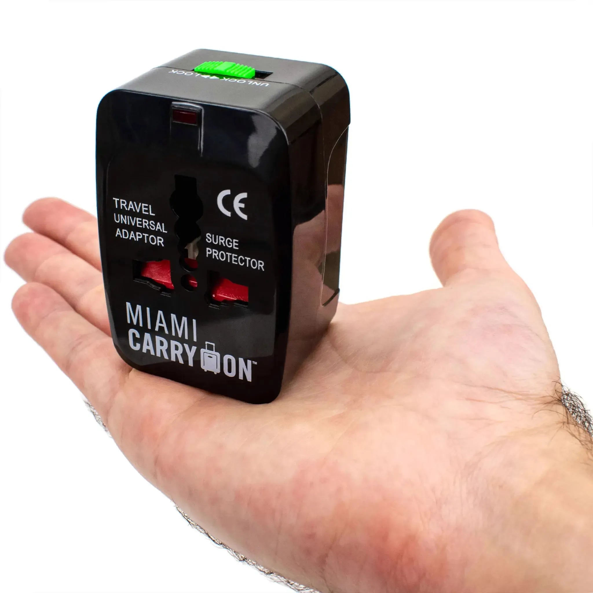 Travel universal adapter with surge protector held in a hand, branded 'Miami Carry On'.