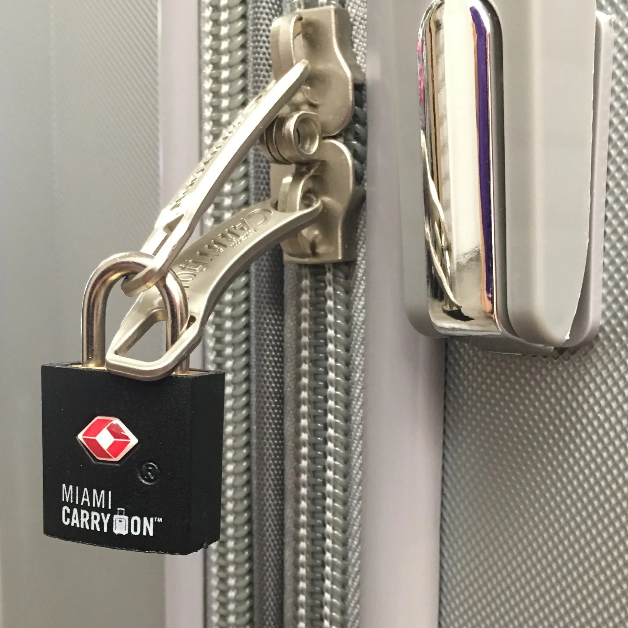 Lock attached to a suitcase with 'Miami Carry-On' branding.