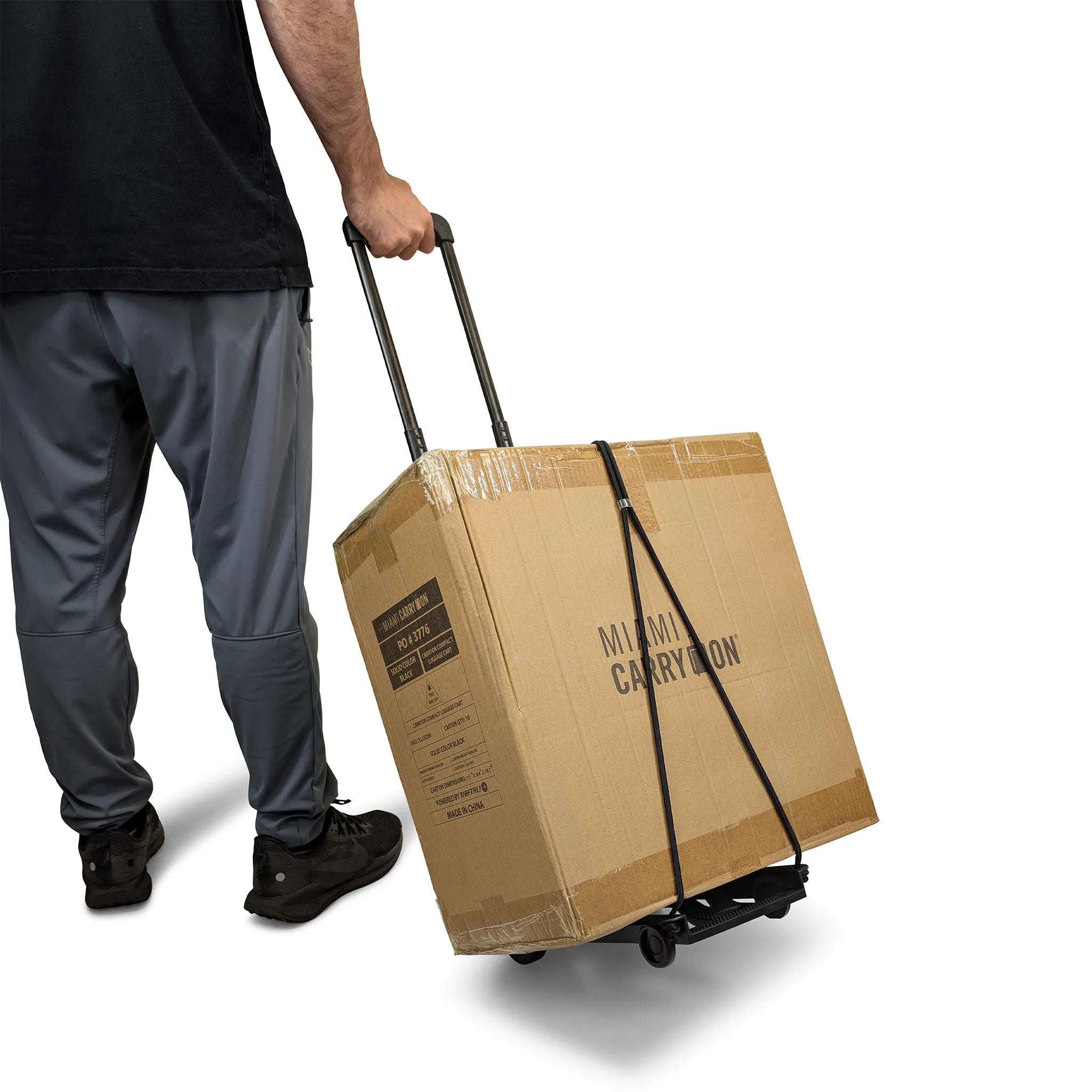 Person pulling a large cardboard box with 'Miami Carry-On' branding on a white background