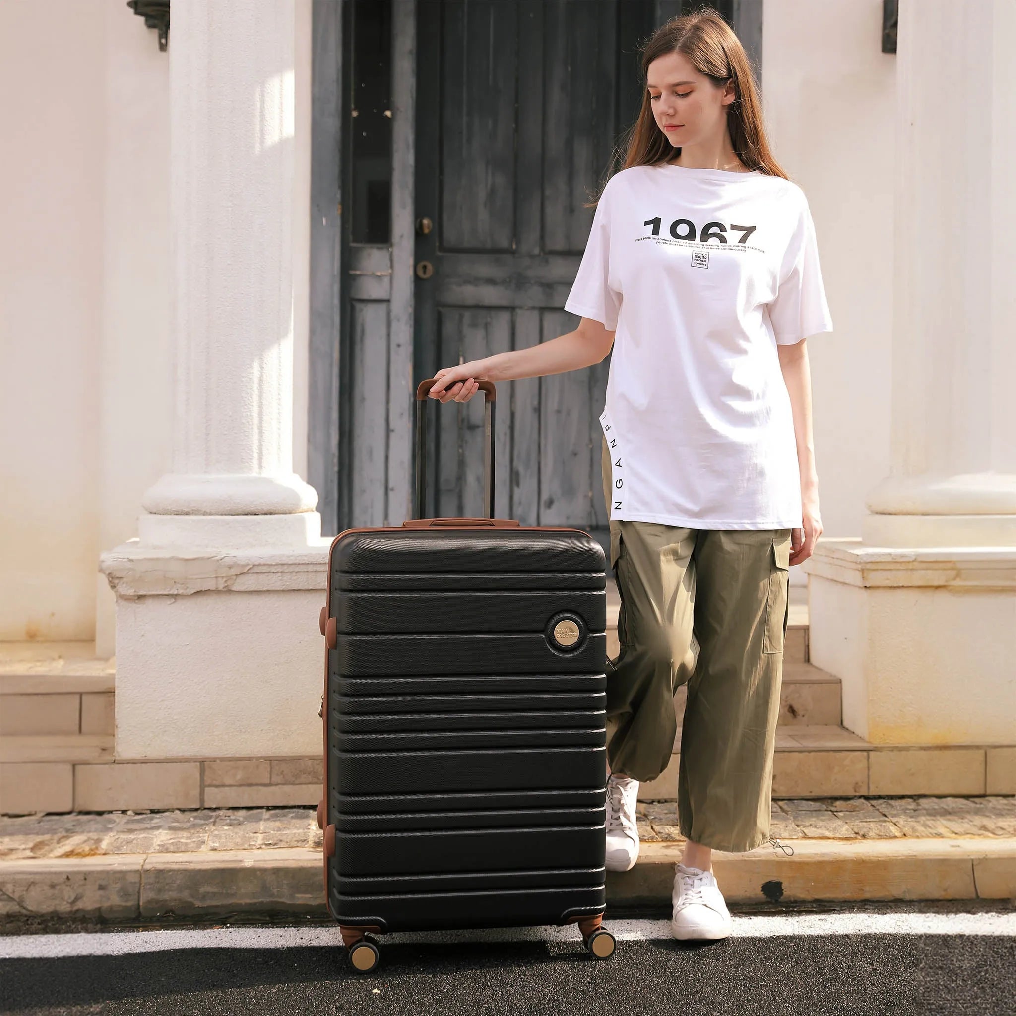 Person pulling a black suitcase on a street with classical architecture in the background