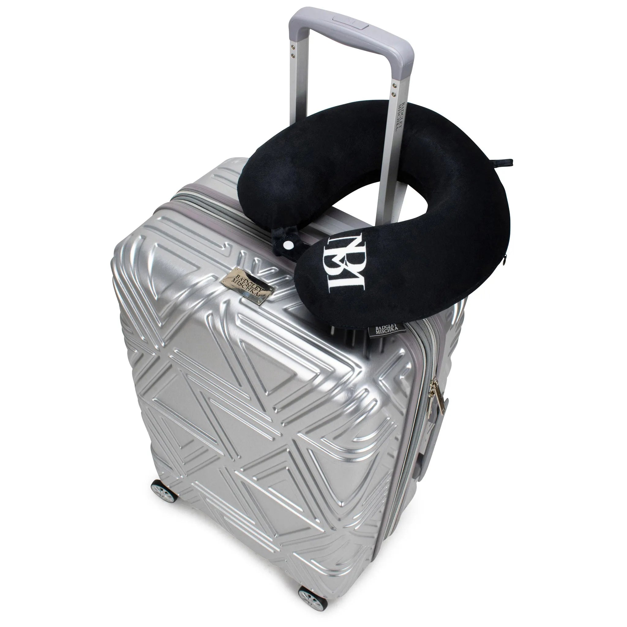 Silver suitcase with a black neck pillow on a white background