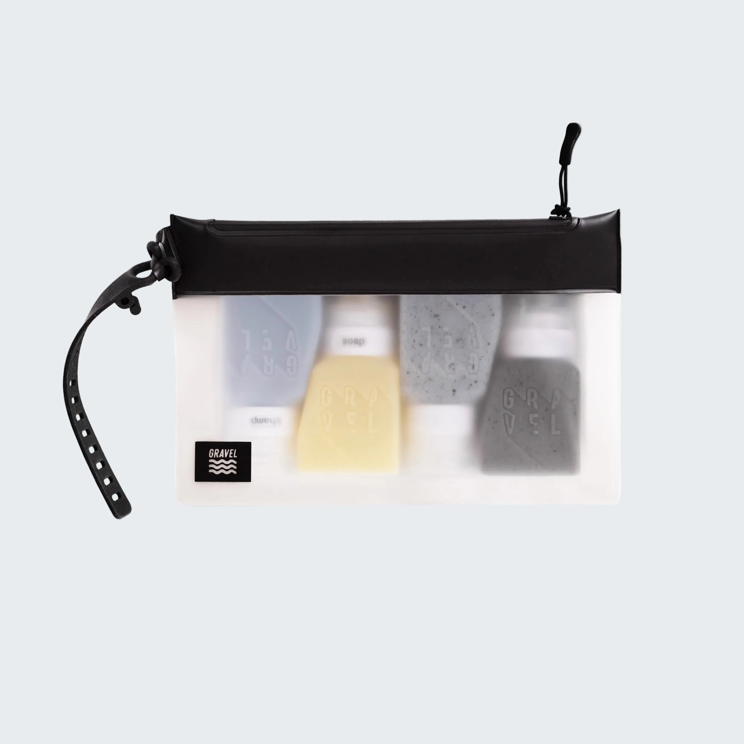 Clear travel pouch with black zipper containing various toiletries on a white background