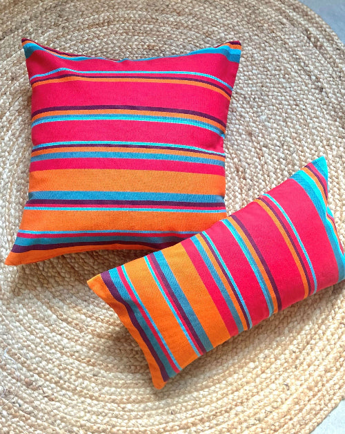 Two colorful striped pillows on a woven surface