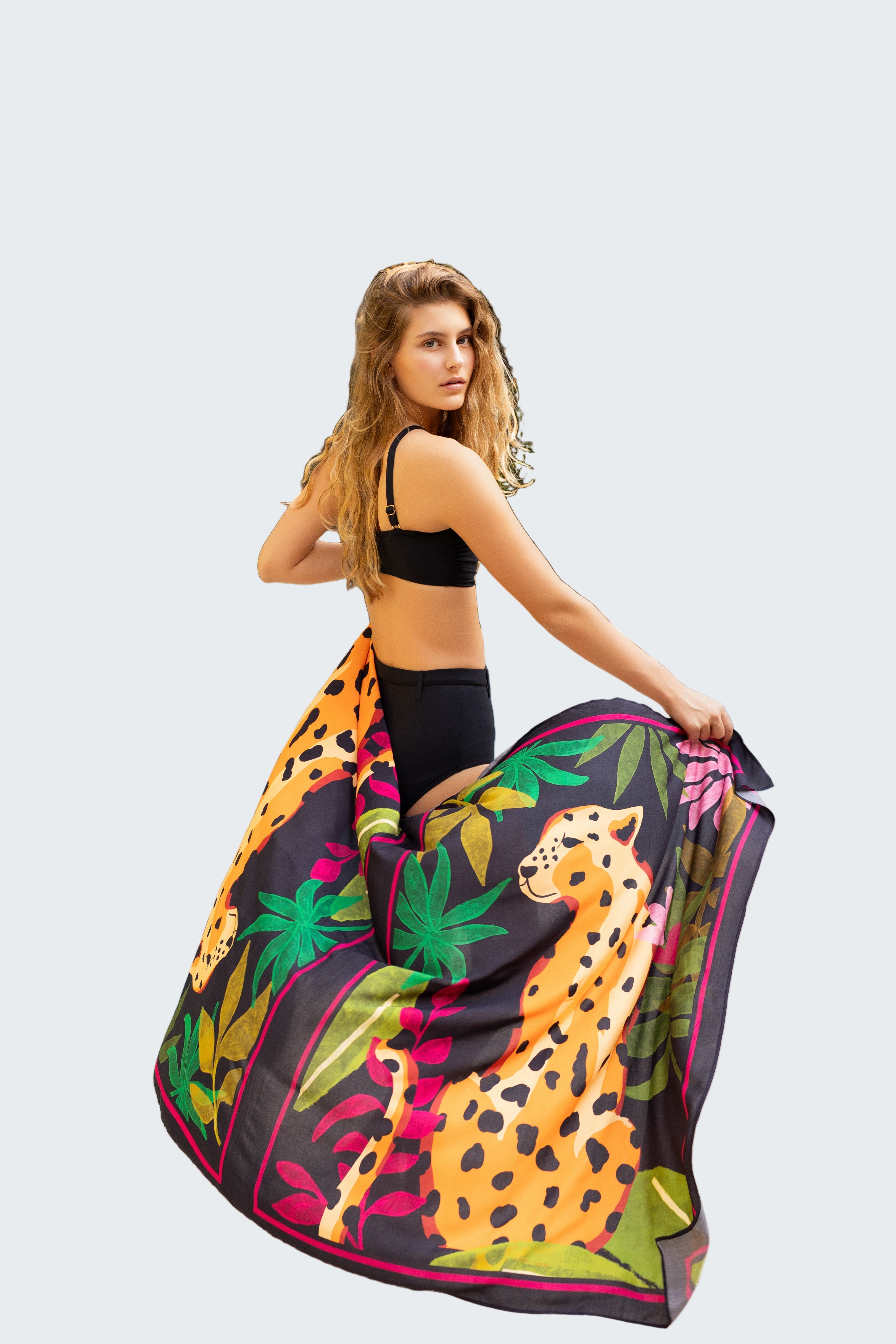 Woman holding a colorful towel with leopard print by a poolside