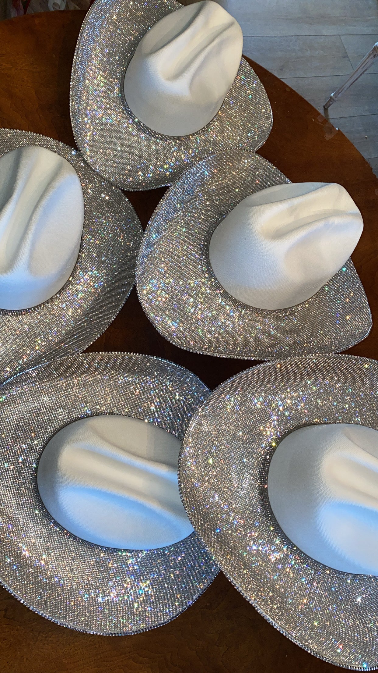 White objects on glittery silver bases arranged on a wooden surface.