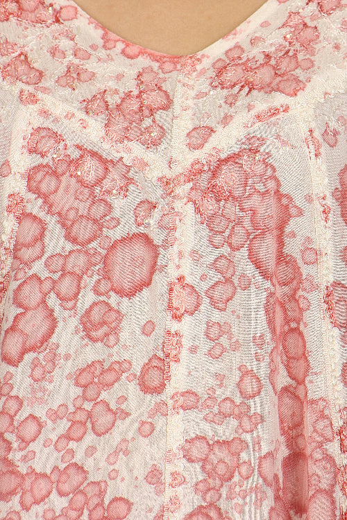 Close-up of a textured fabric with pink and red patterns on a white background