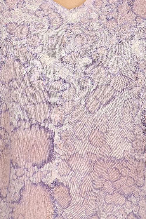 Close-up of a textured fabric with a pattern of raised, rounded shapes in shades of purple and beige.