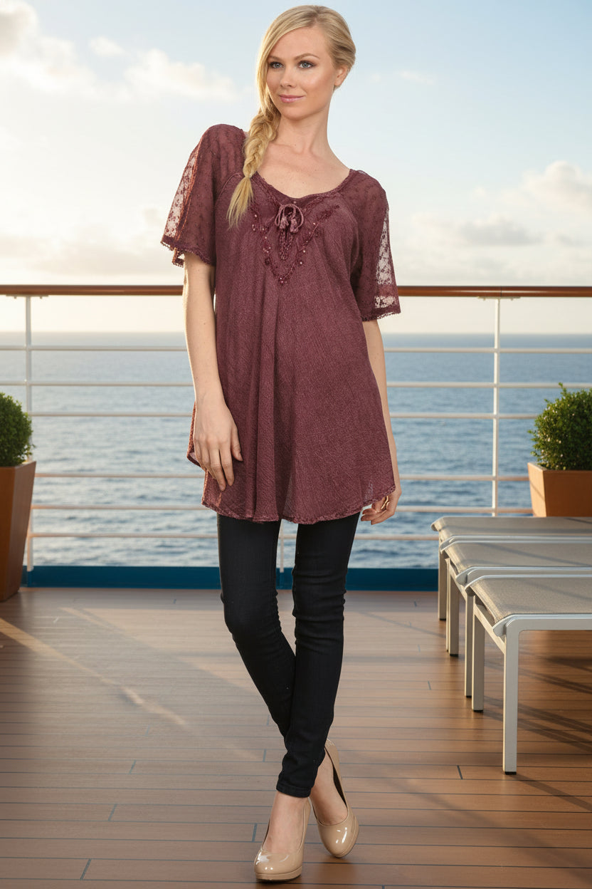 Woman wearing a burgundy lace top with black leggings on a white background