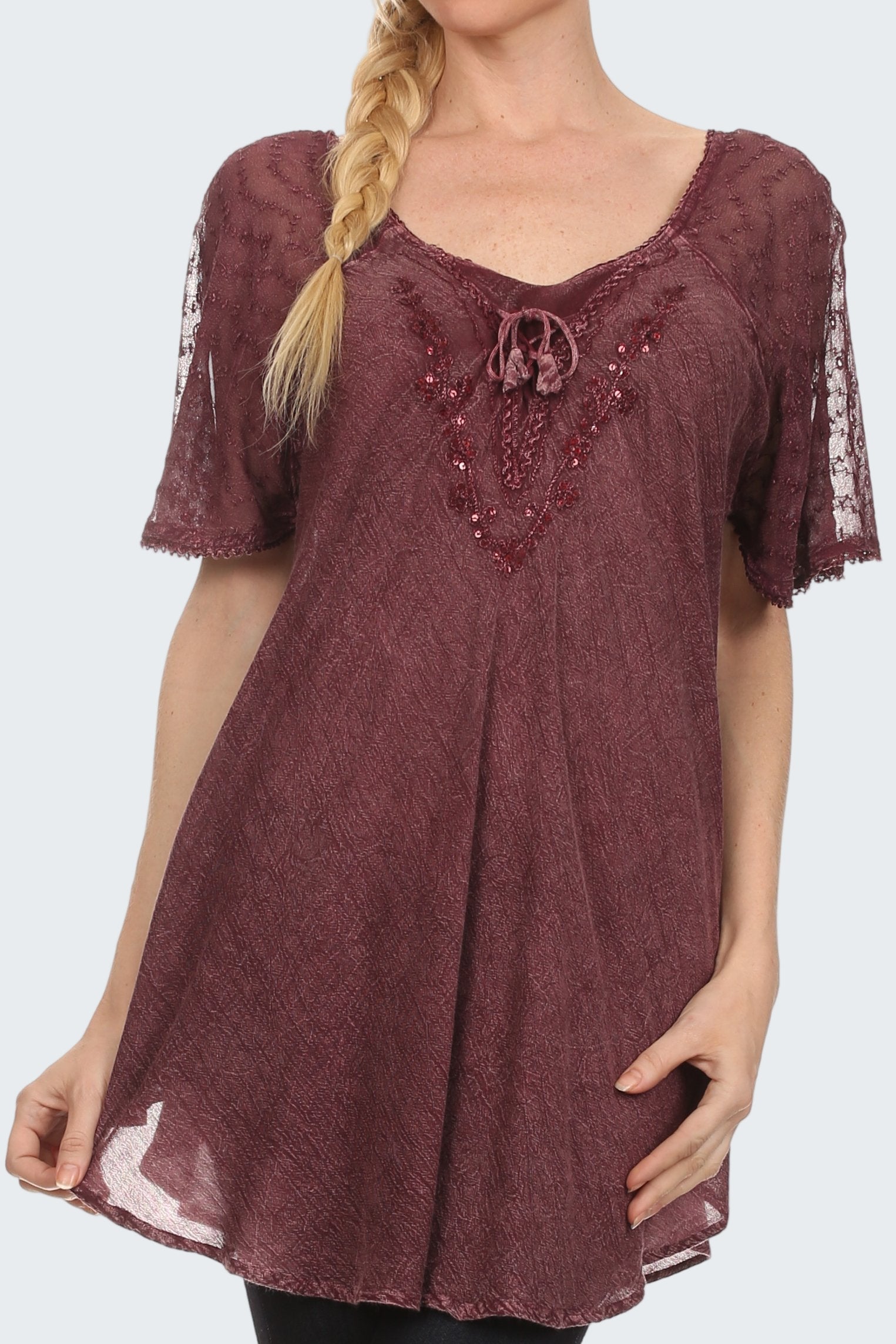 Woman wearing a burgundy lace top with embellishments on a white background