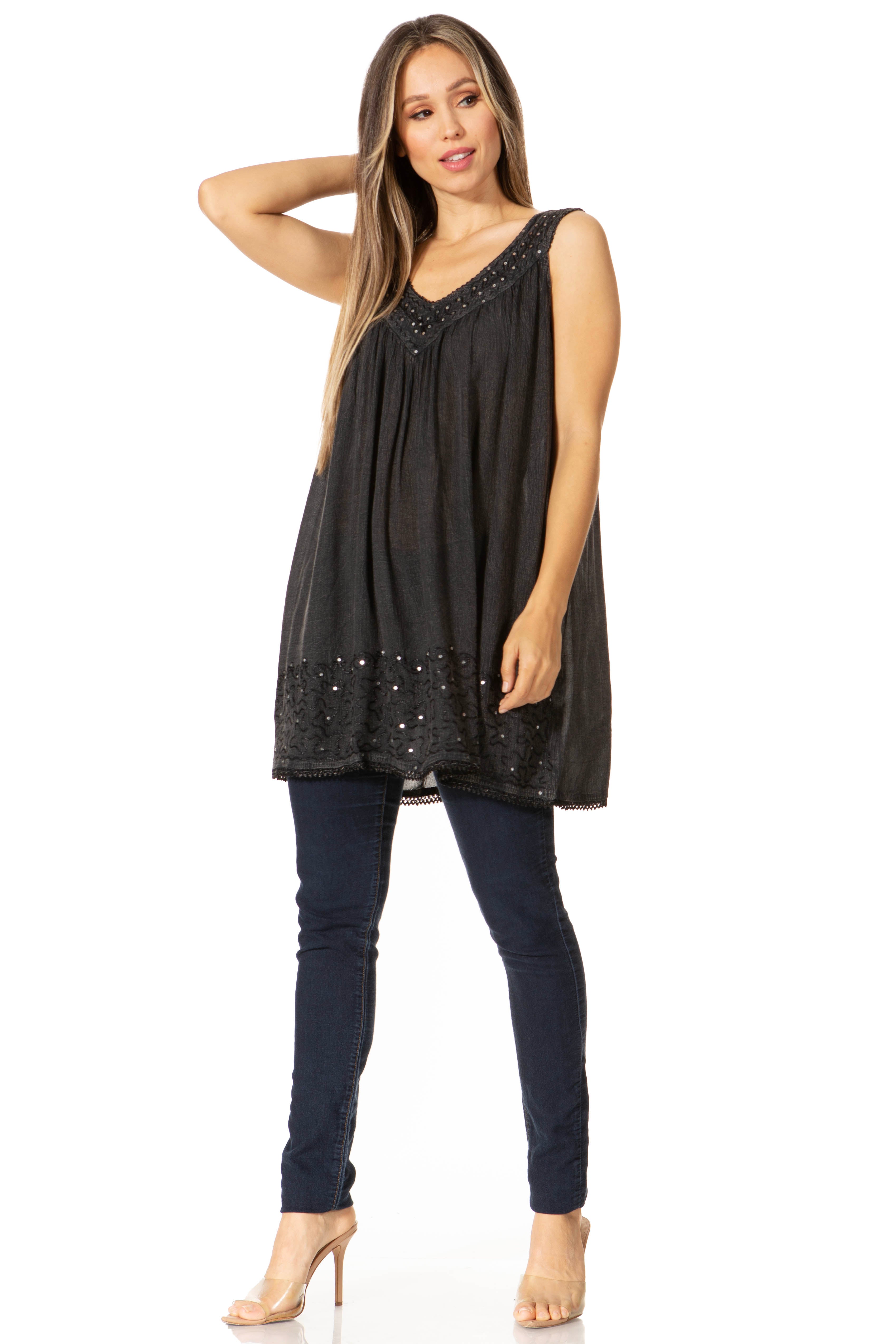 Woman wearing a black sleeveless top and dark jeans on a white background