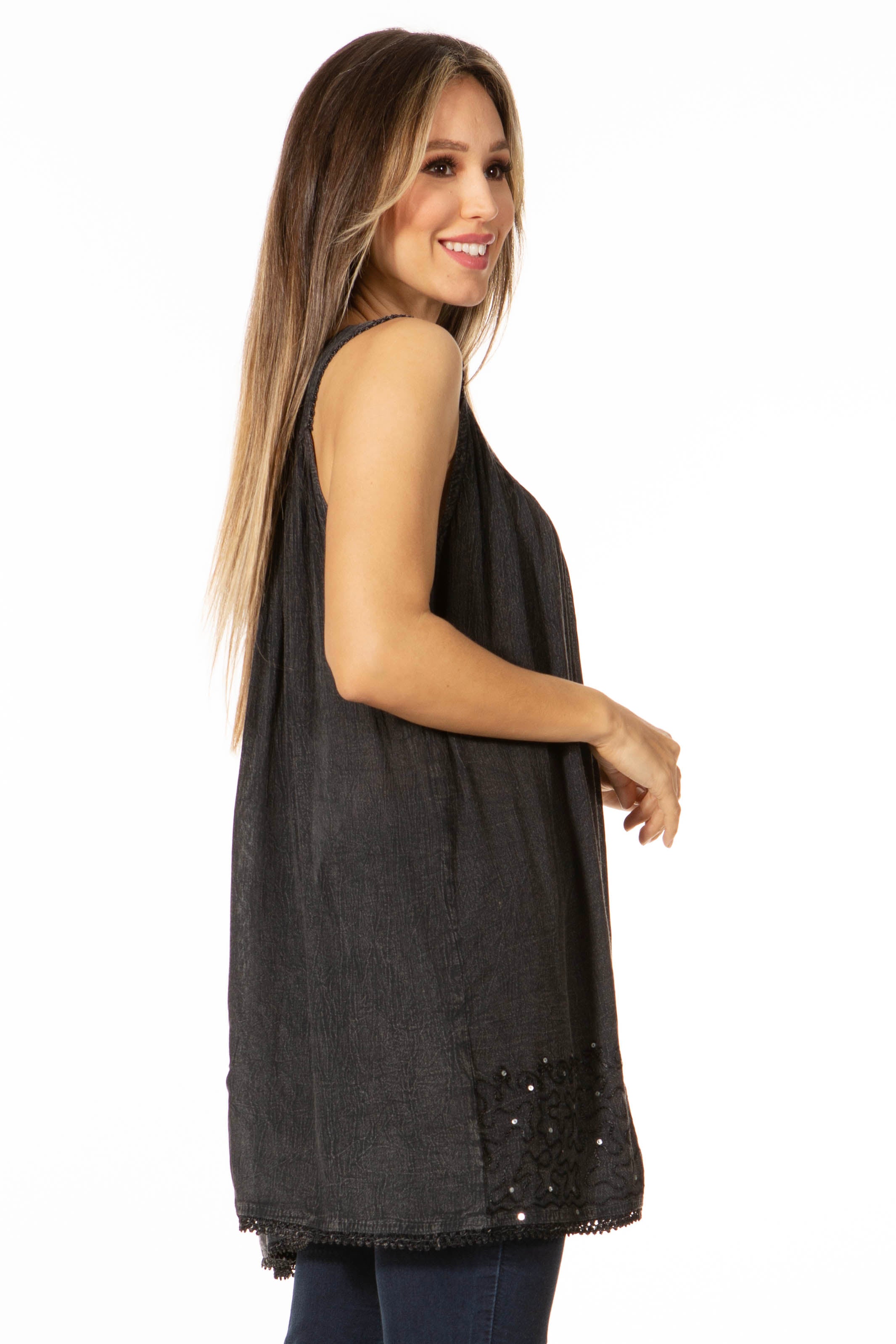 Woman wearing a black sleeveless top with embellishments on a white background