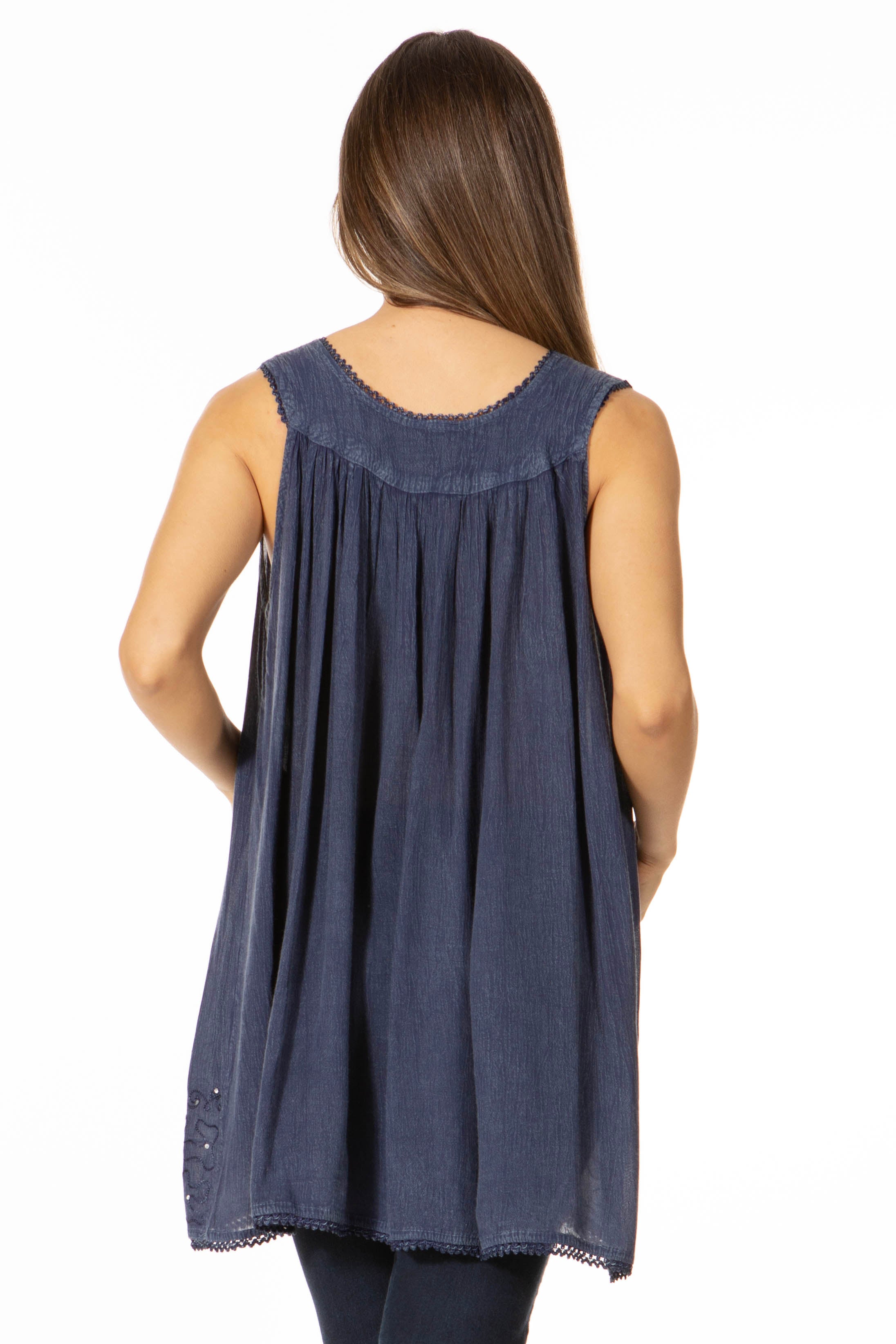Woman wearing a sleeveless denim top with a white background