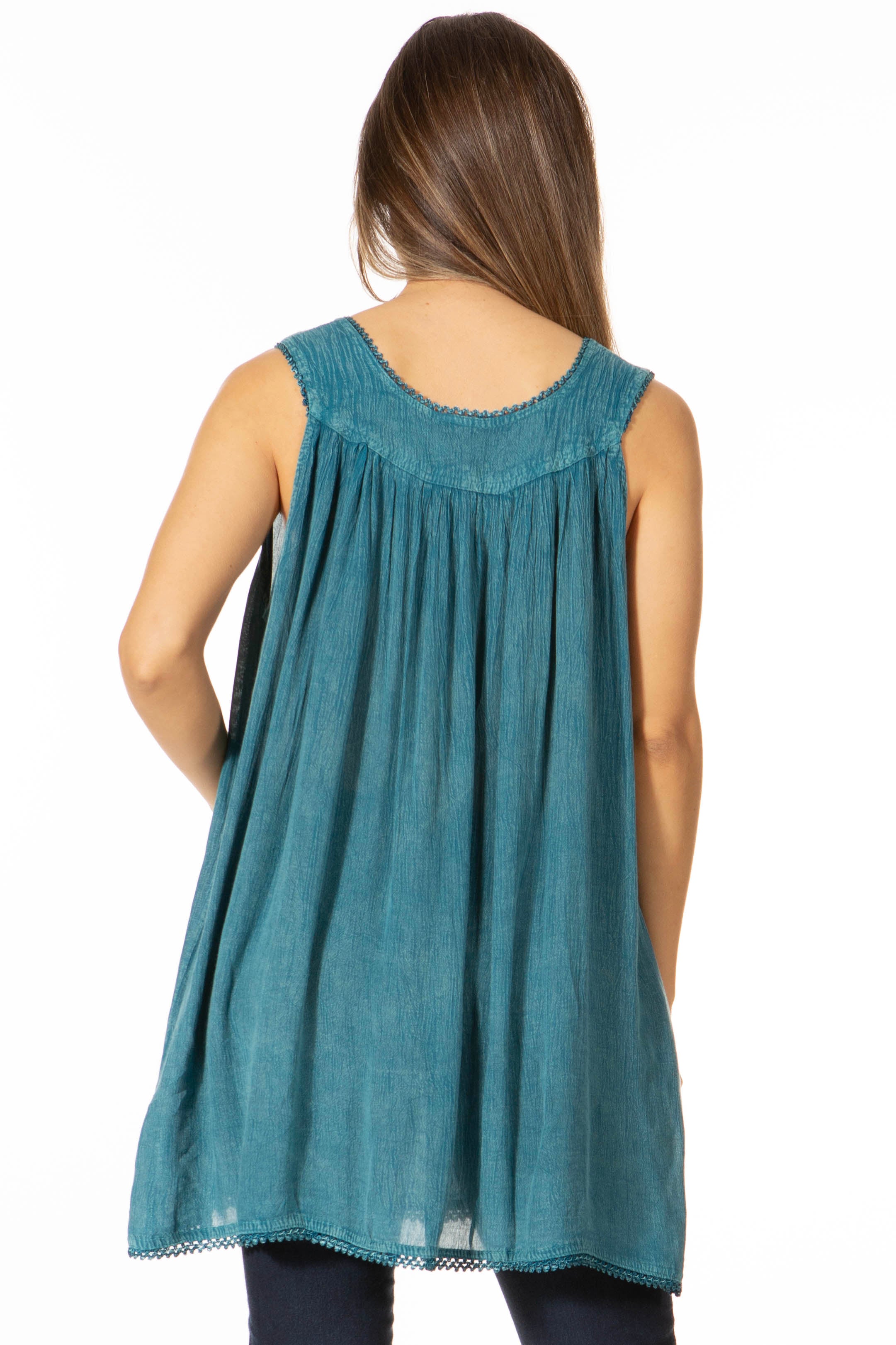 Woman wearing a teal sleeveless top with lace details on a white background