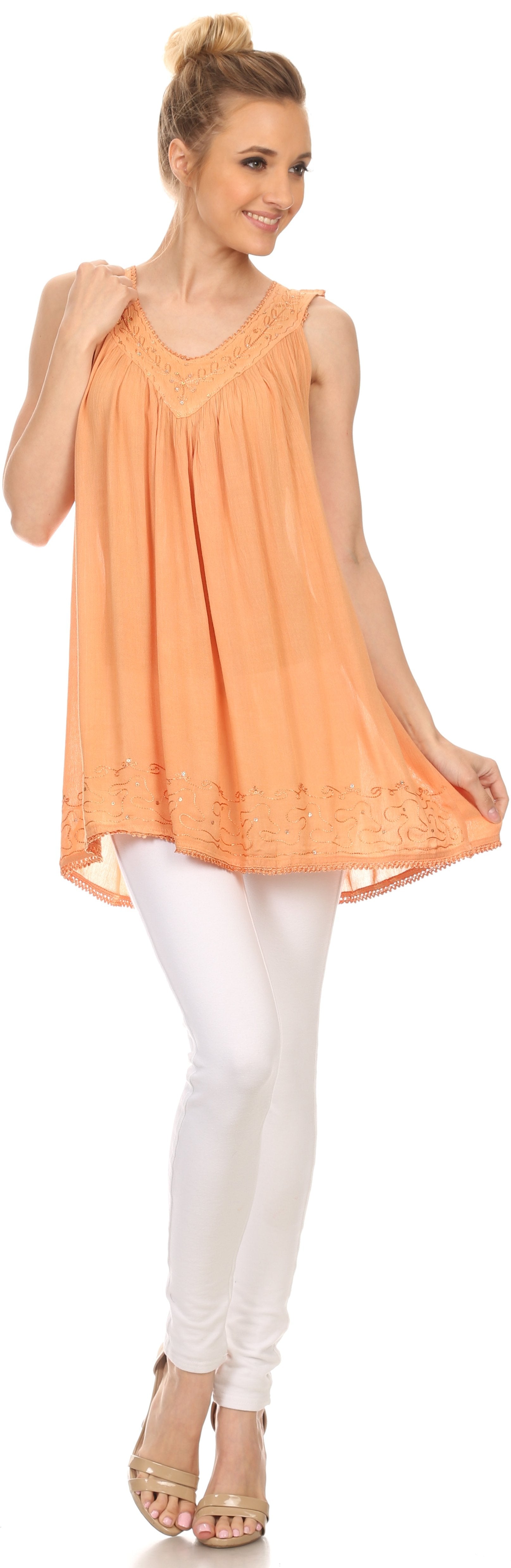 Woman wearing an orange sleeveless top and white pants on a white background