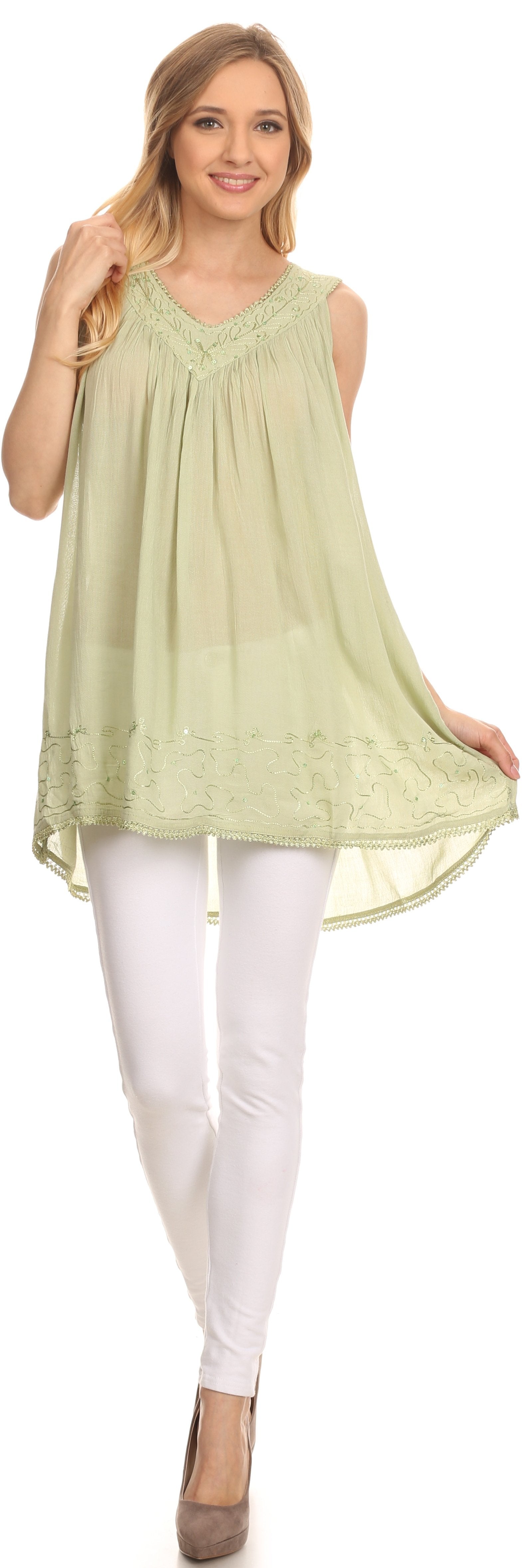 Woman wearing a light green sleeveless top and white pants on a white background