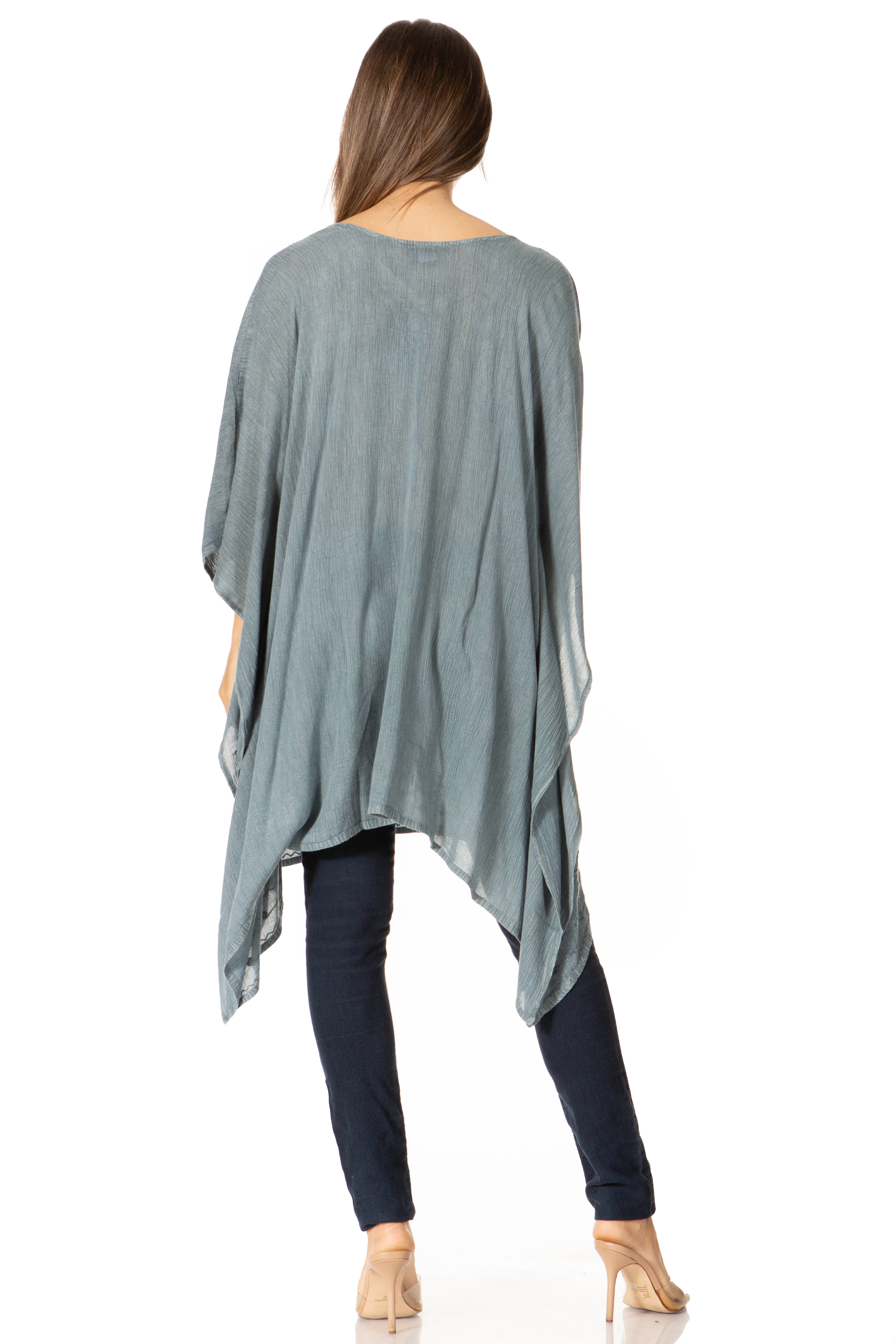 Woman wearing a light blue poncho over dark pants on a white background