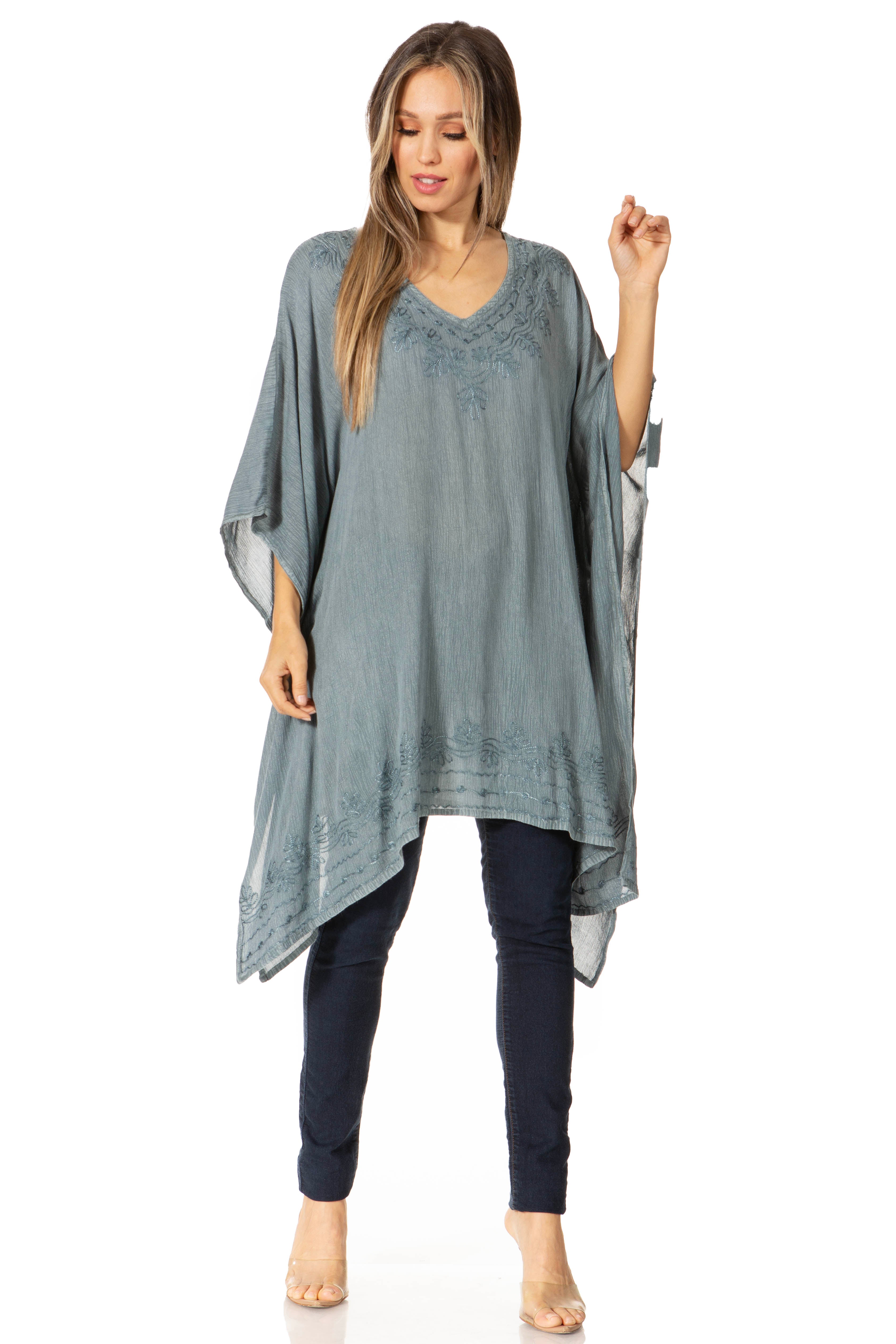 Woman wearing a gray poncho over a black outfit on a white background