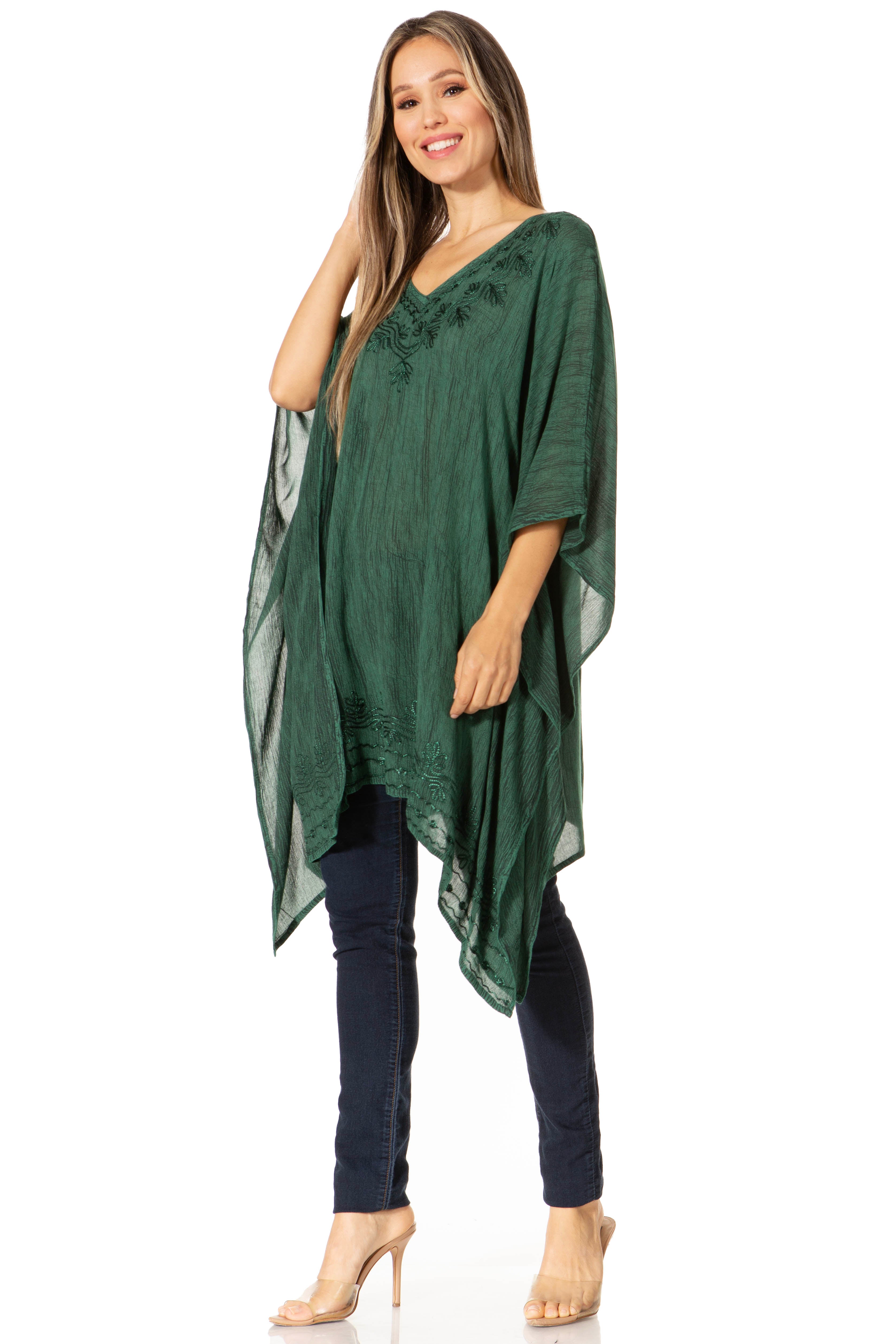 Woman wearing a green poncho over a navy outfit on a white background