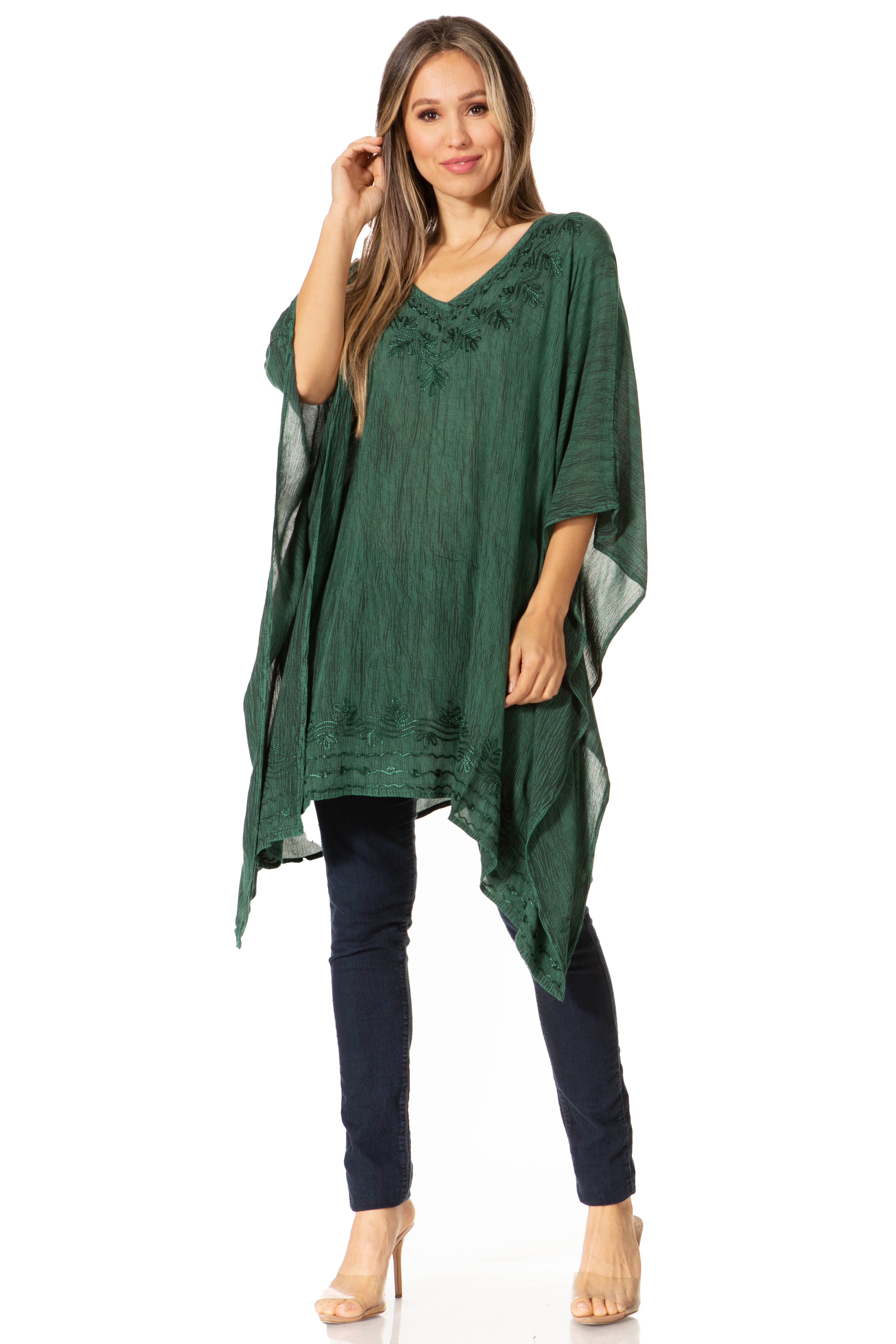Woman wearing a green poncho over a navy outfit on a white background