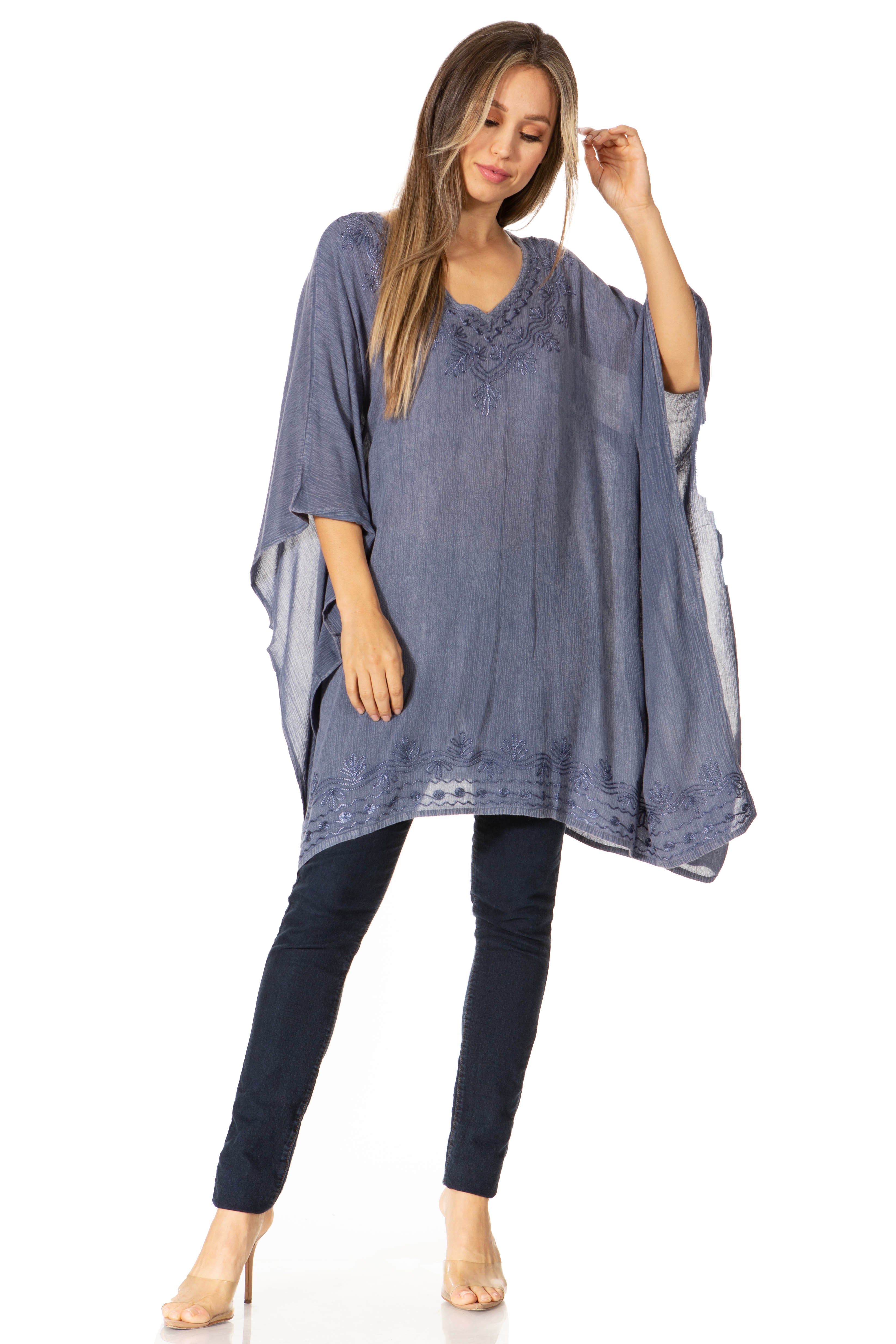 Woman wearing a blue poncho over a dark outfit on a white background