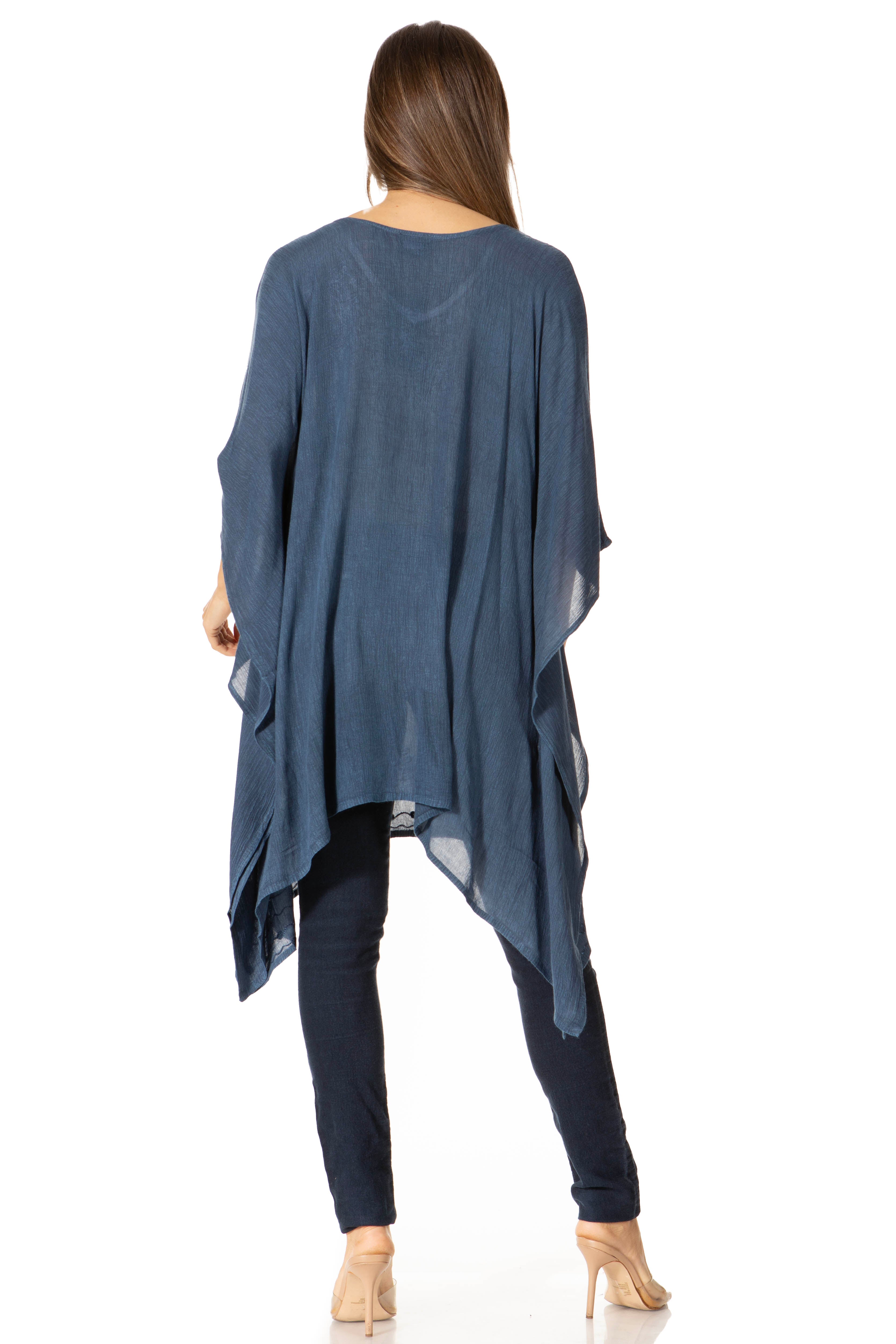Woman wearing a blue poncho over dark pants on a white background
