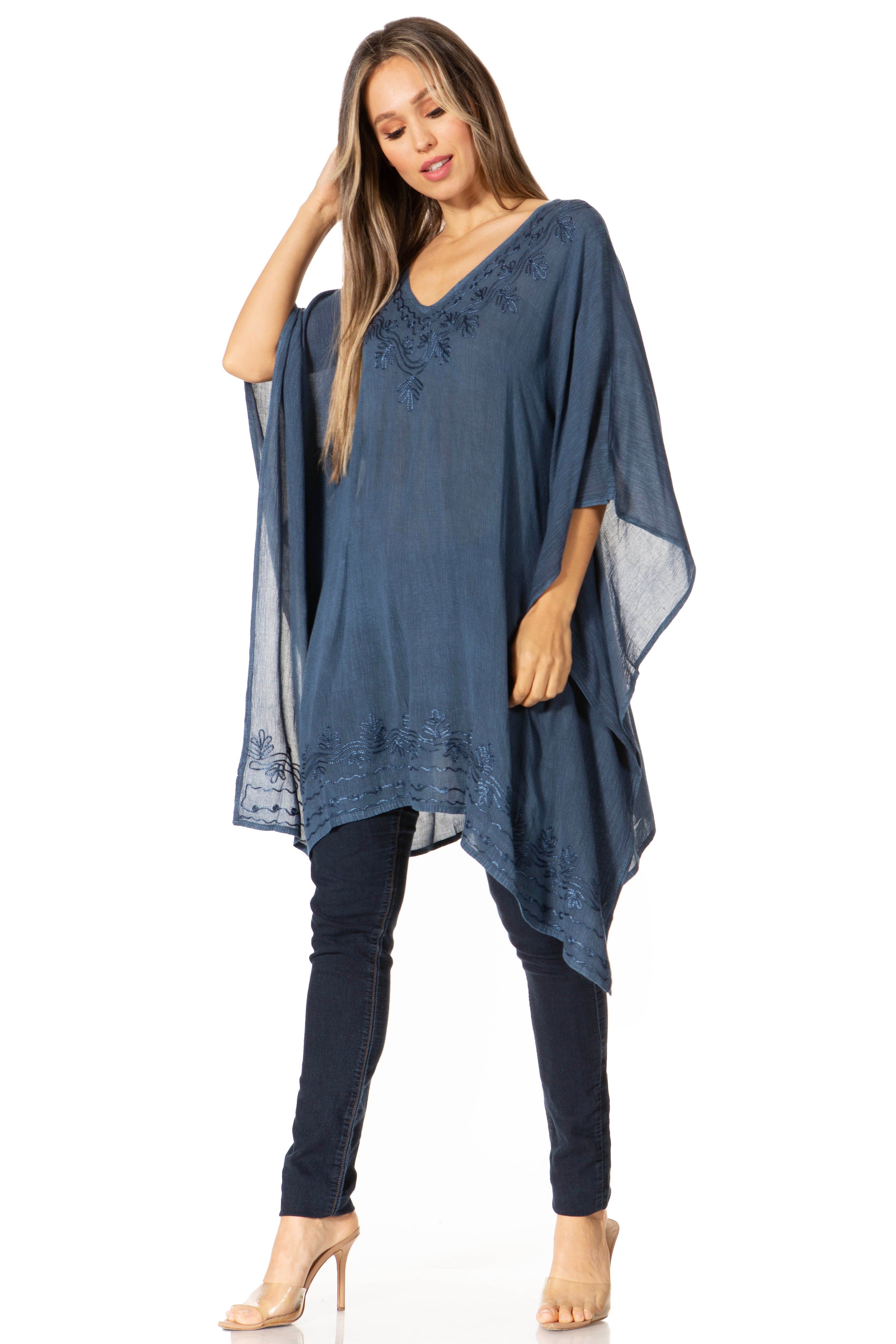 Woman wearing a blue poncho over a dark outfit on a white background