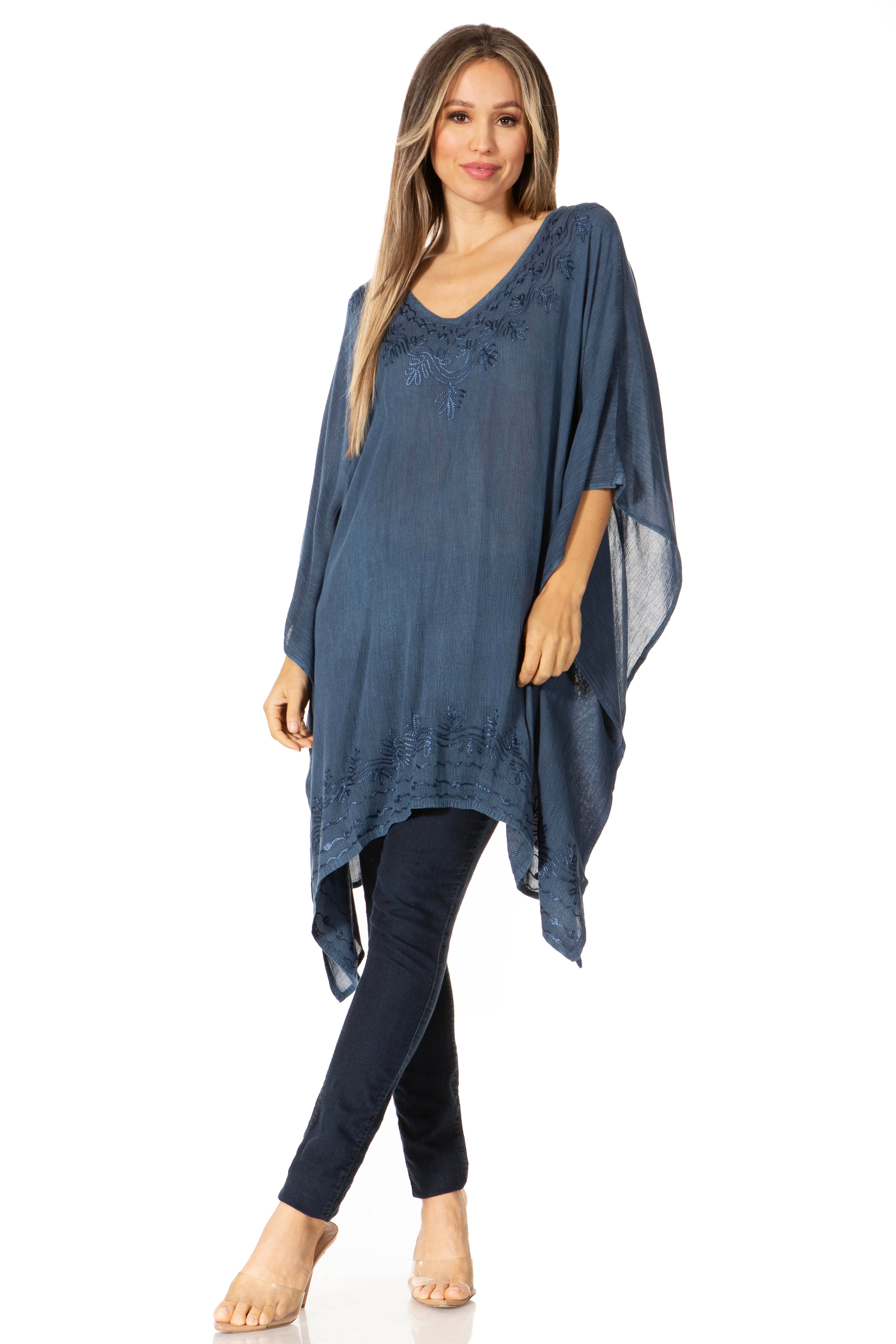 Woman wearing a blue poncho over black pants on a white background