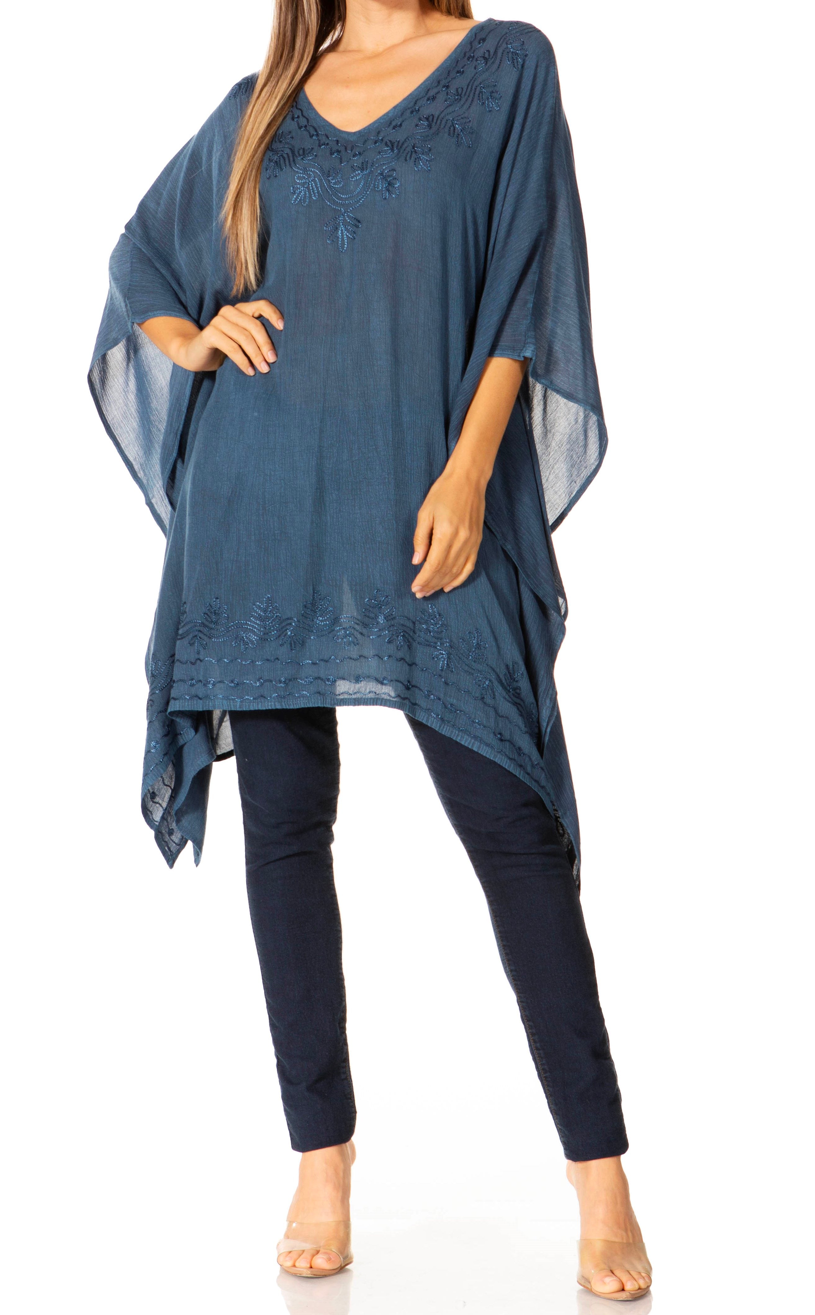 Woman wearing a blue poncho over a dark outfit on a white background