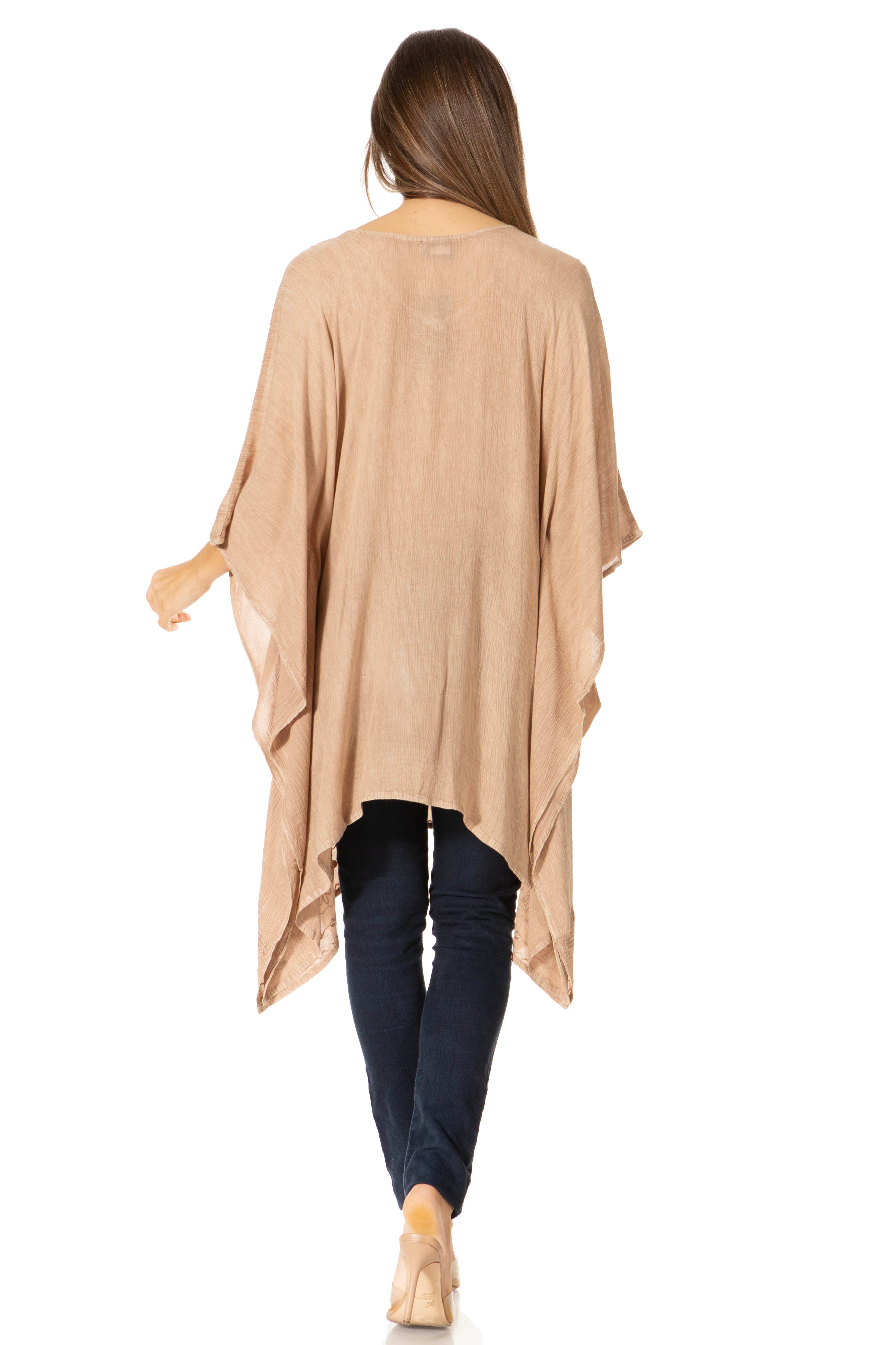 Woman wearing a beige poncho over a dark outfit on a white background