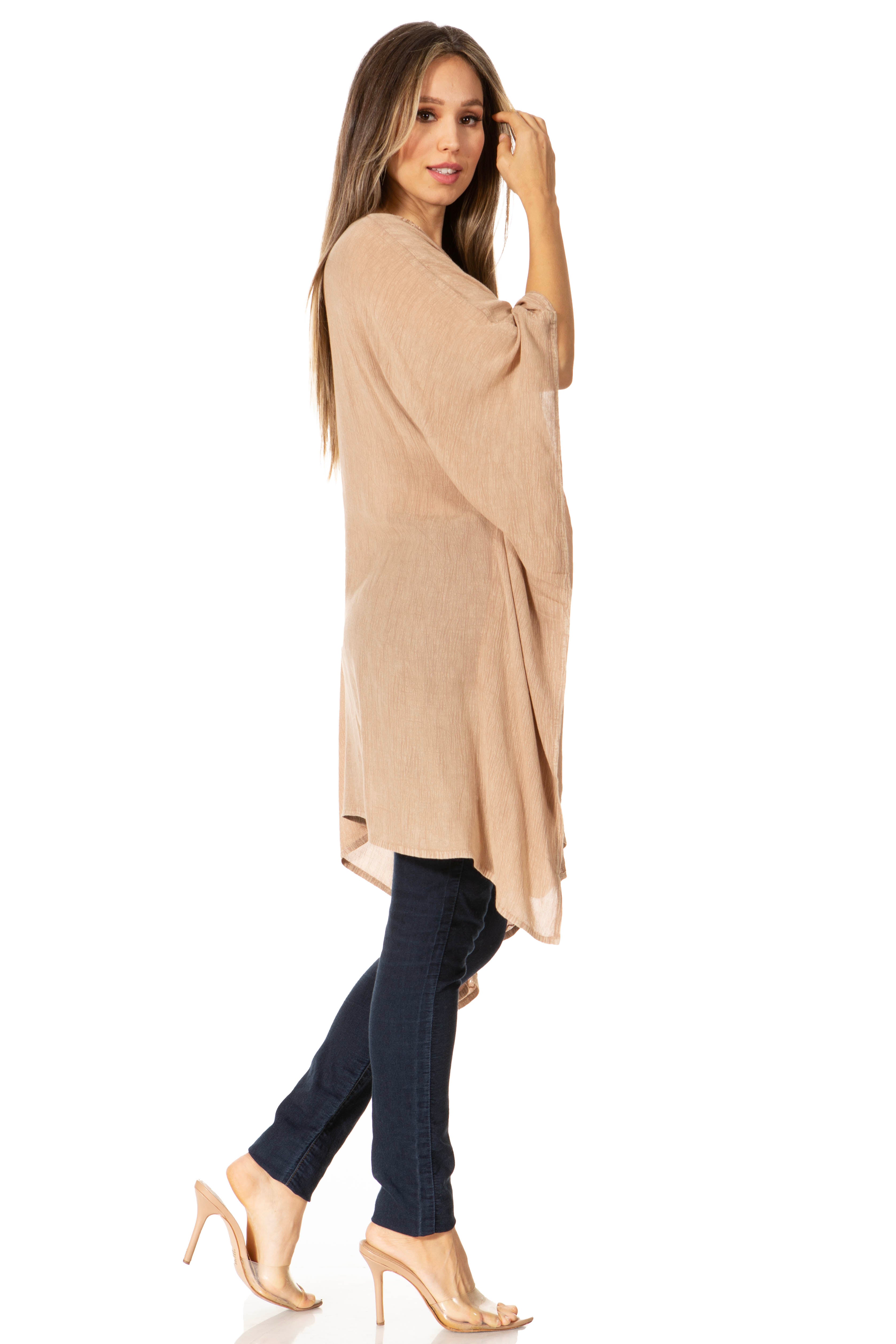 Woman wearing a beige long sweater and dark jeans on a white background
