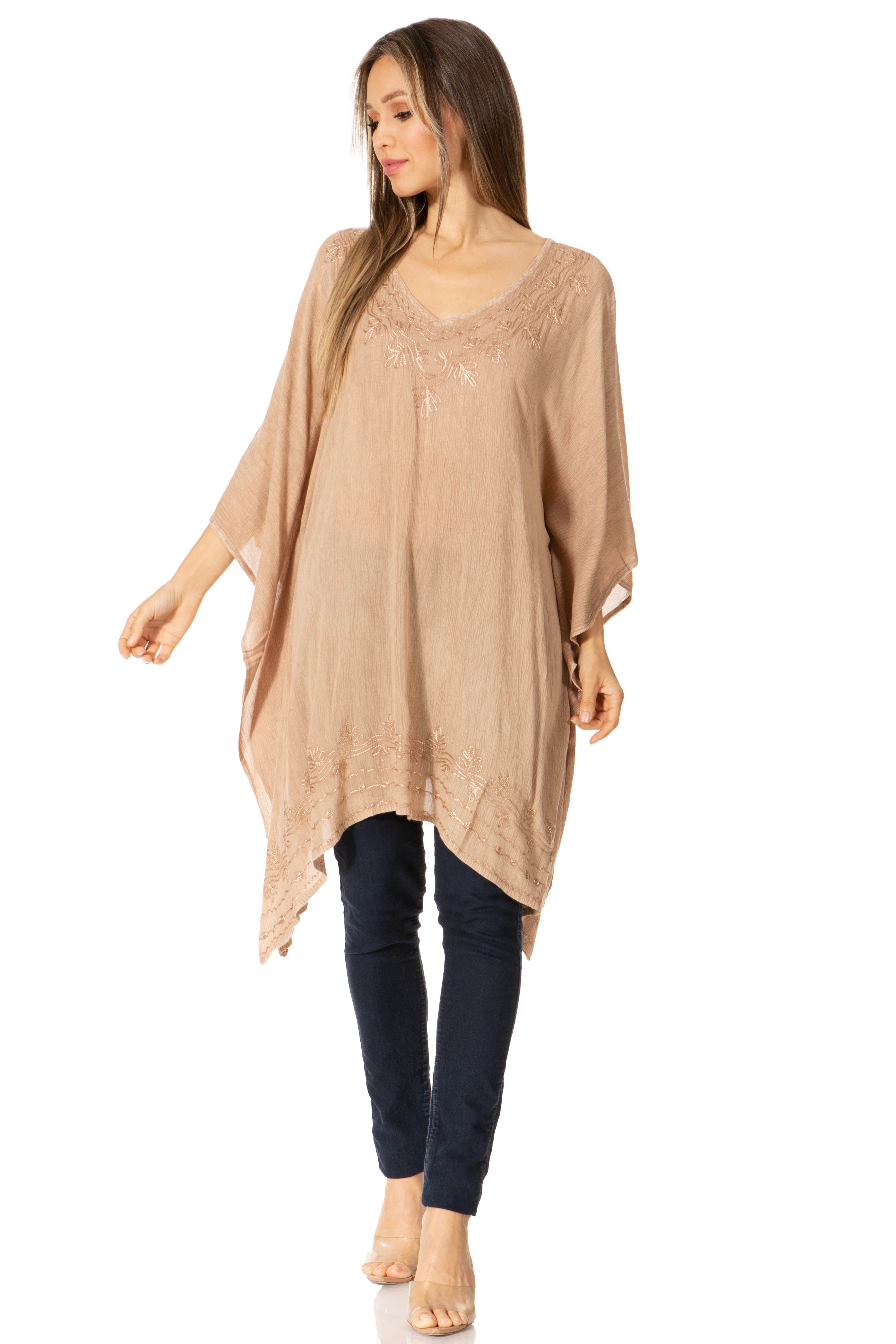 Woman wearing a beige long top and dark pants on a white background